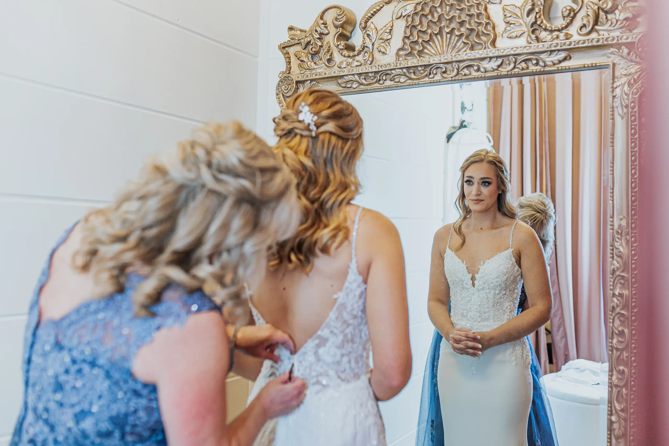 Getting Ready: the bride being buttoned in at the mirror, before their wedding at The Venue at Sharp Mountain in Jasper, GA