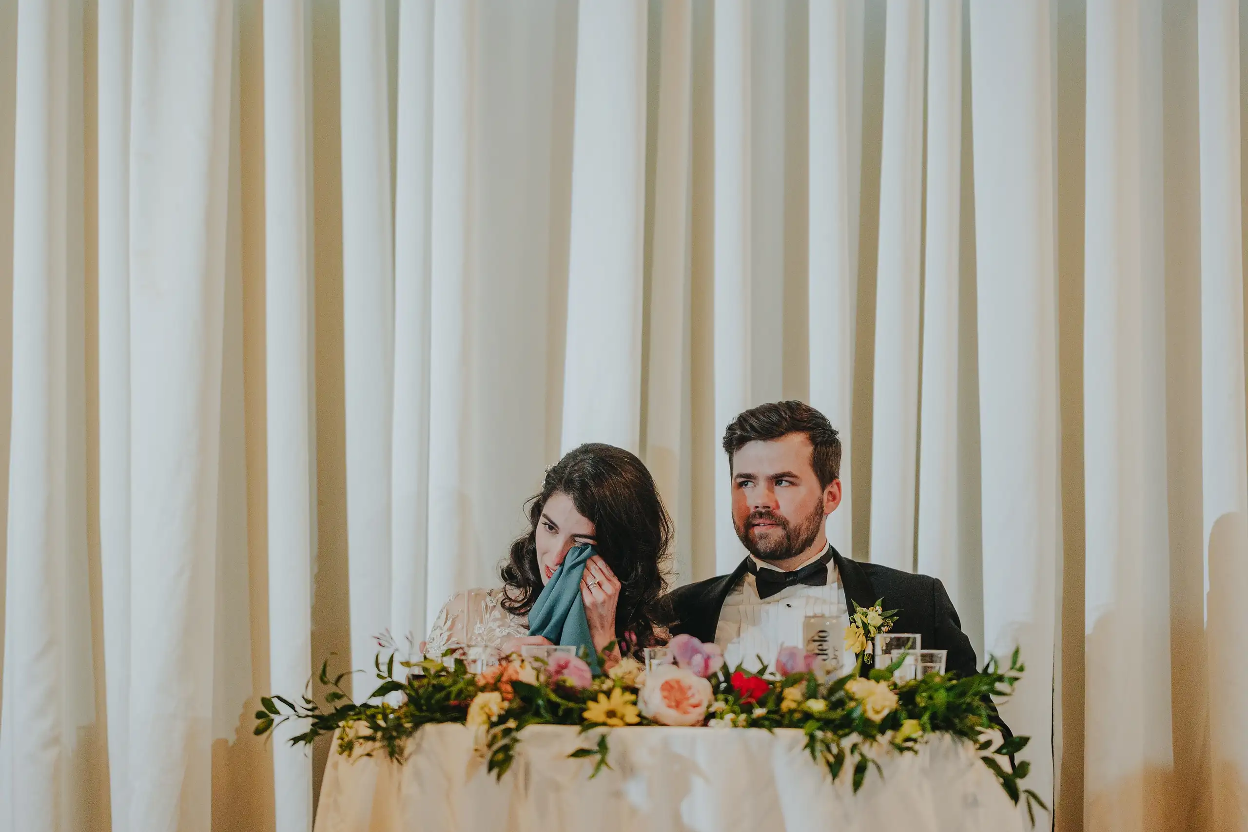 Wedding Reception: the couple at their flower-trimmed sweetheart table, at their wedding at the Trolley Barn in Atlanta, GA