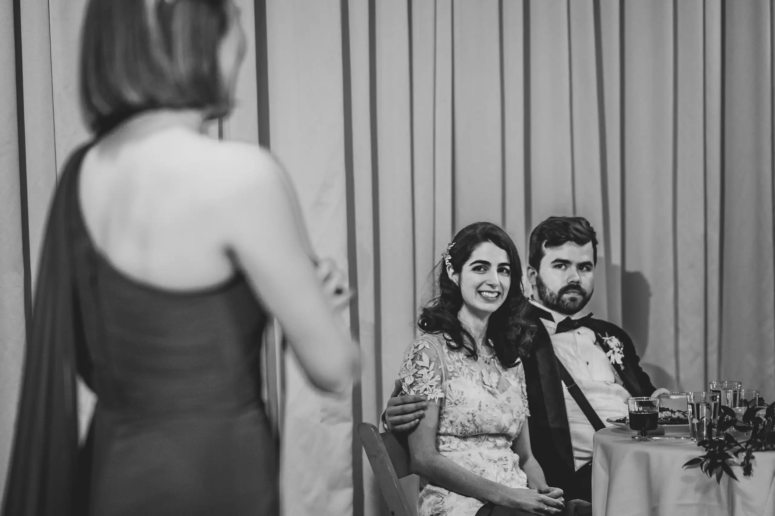 Wedding Reception: the couple listening to a speech, in black and white, at their wedding at the Trolley Barn in Atlanta, GA