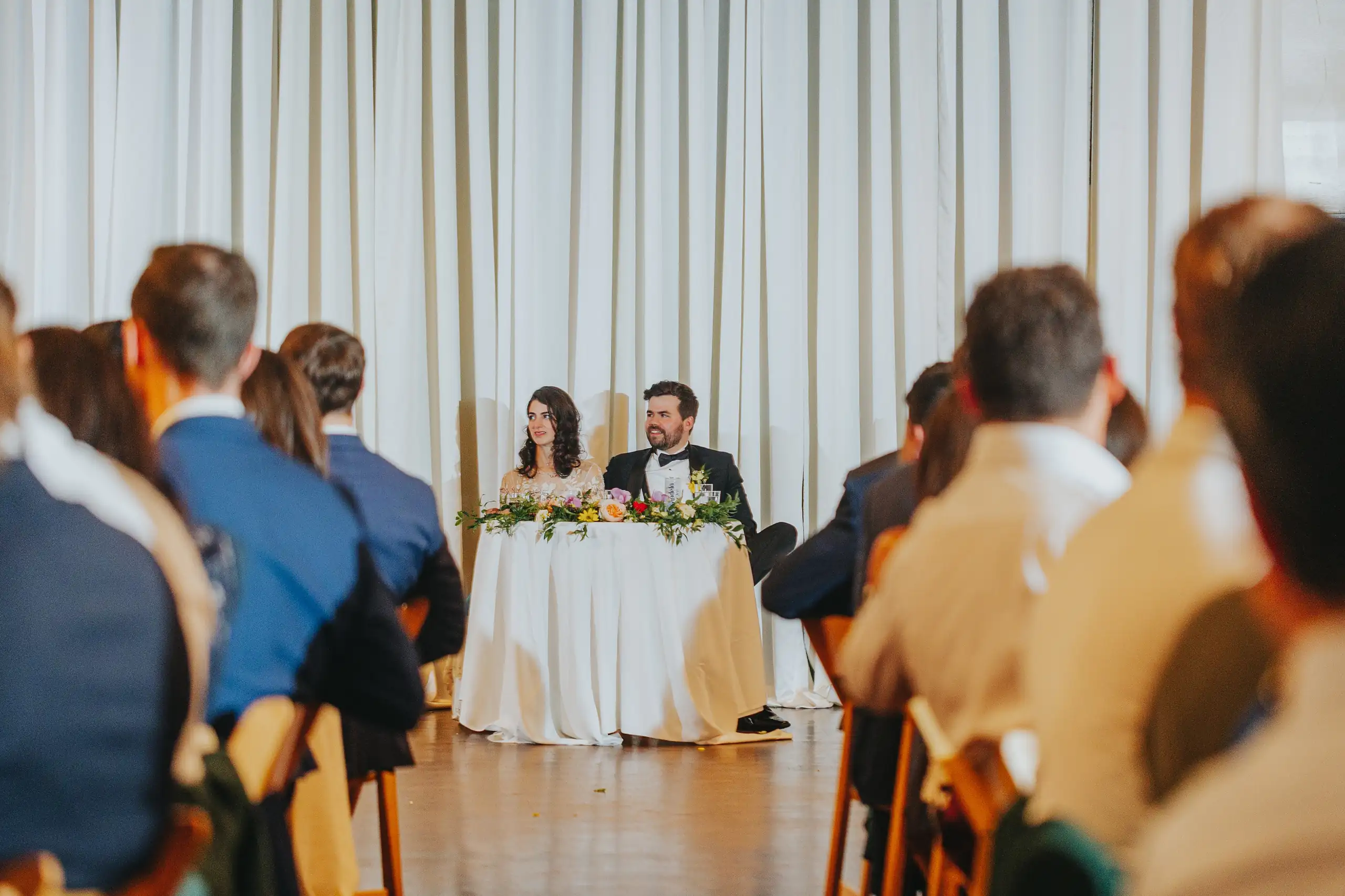 Wedding Reception: the couple at the table as the guests toast, at their wedding at the Trolley Barn in Atlanta, GA
