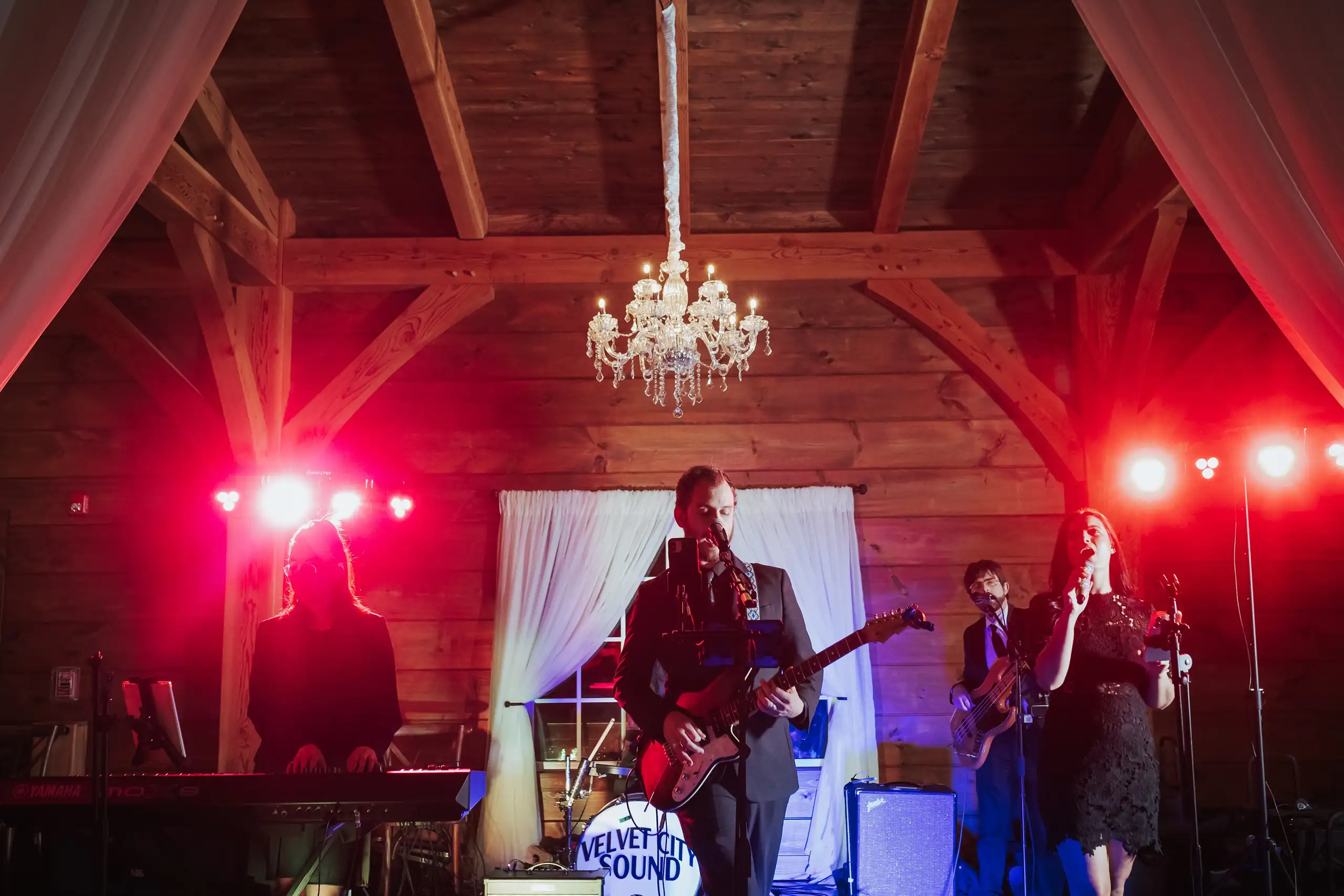 Wedding Reception: the live band playing under red lights, at their wedding at The Venue at Sharp Mountain in Jasper, GA