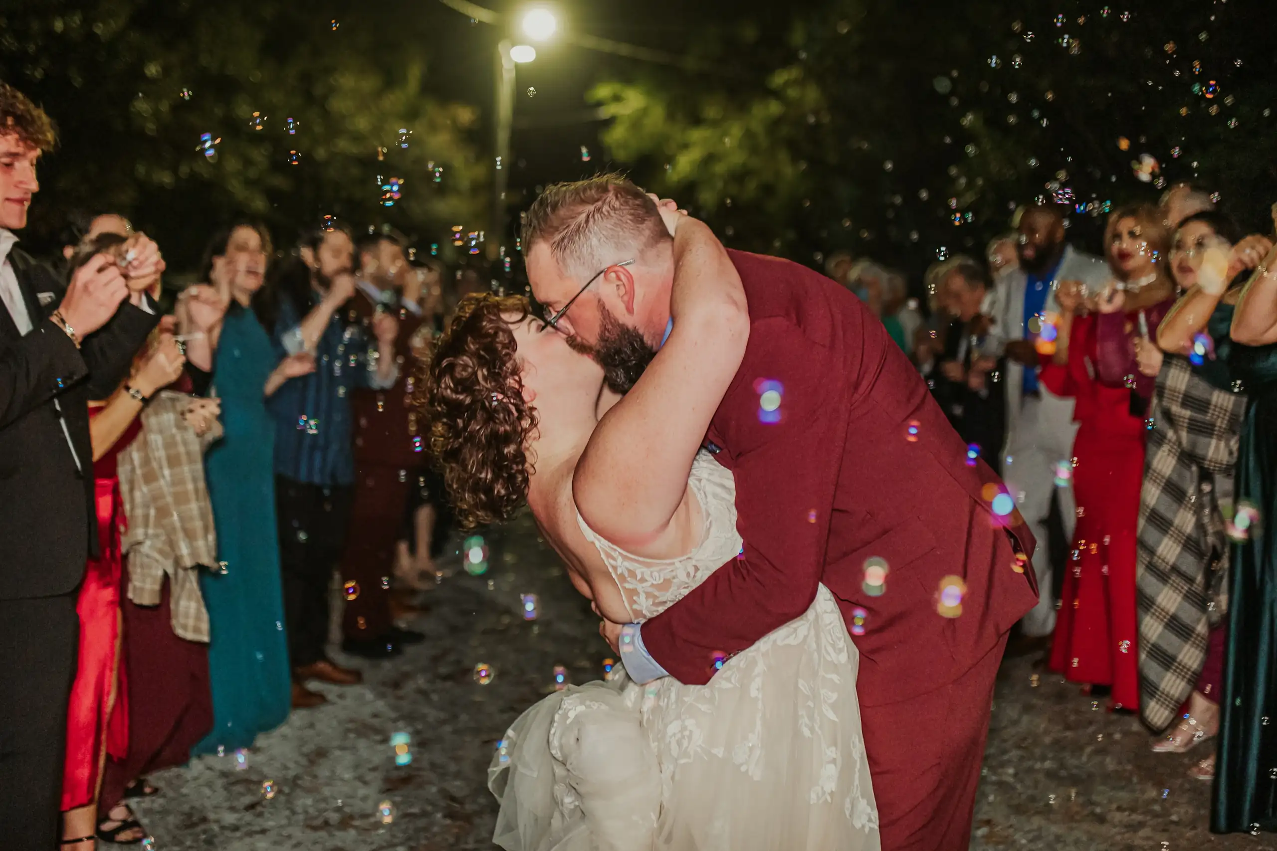 Send-Off: a dip kiss in the bubbles as the guests watch, at their wedding at Wahoo! Grill in Decatur, GA