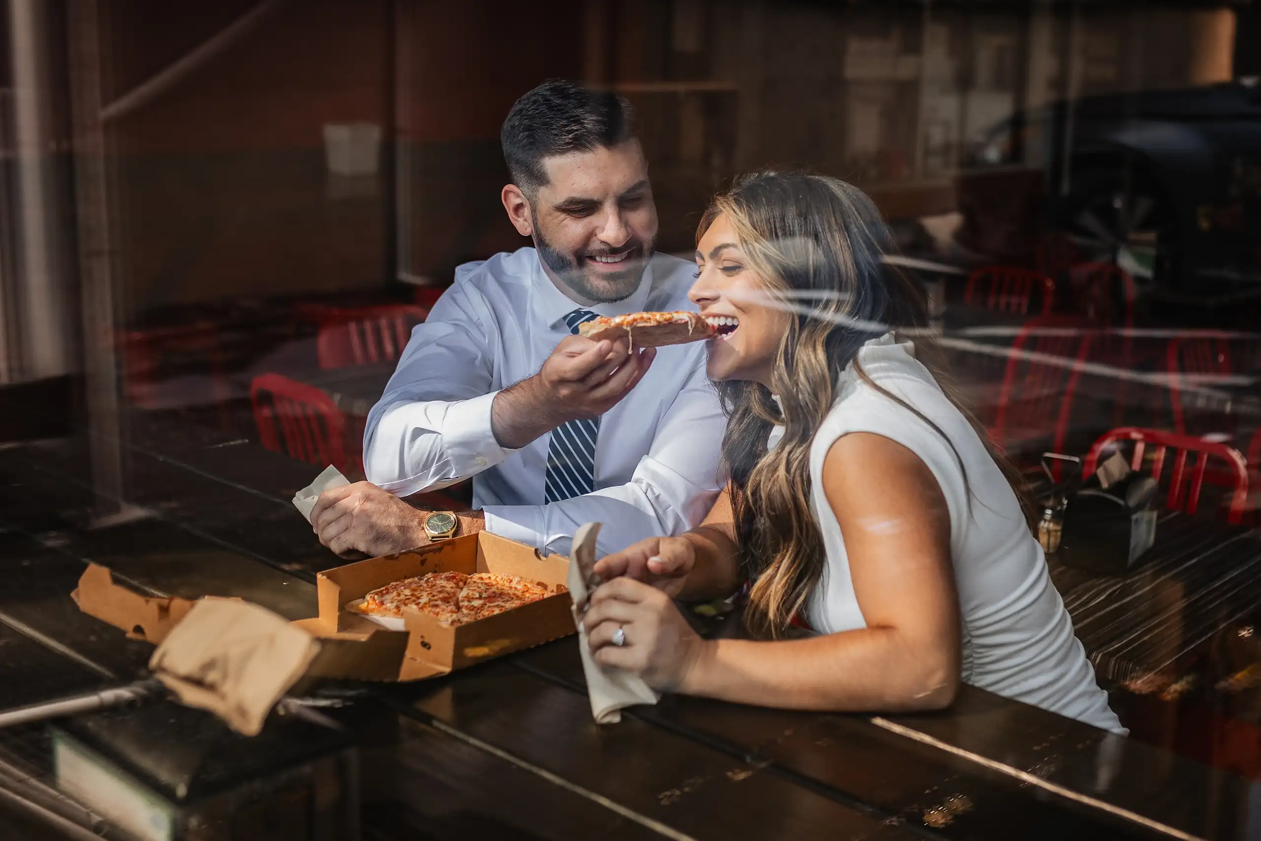 Engagement Portraits: sharing a pizza across the counter, both laughing, during their engagement session