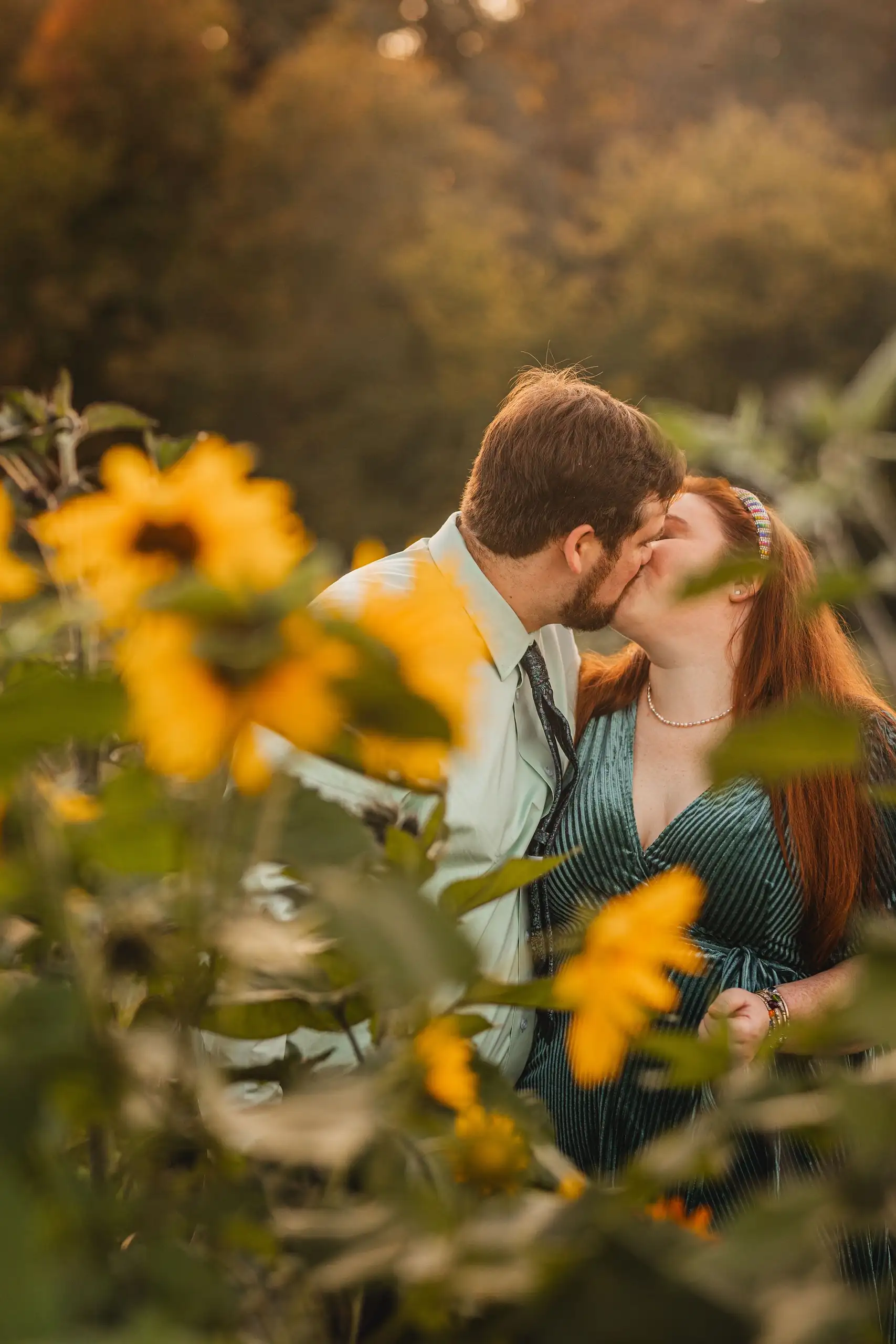Engagement Portraits: a kiss behind the sunflower heads, during their engagement session