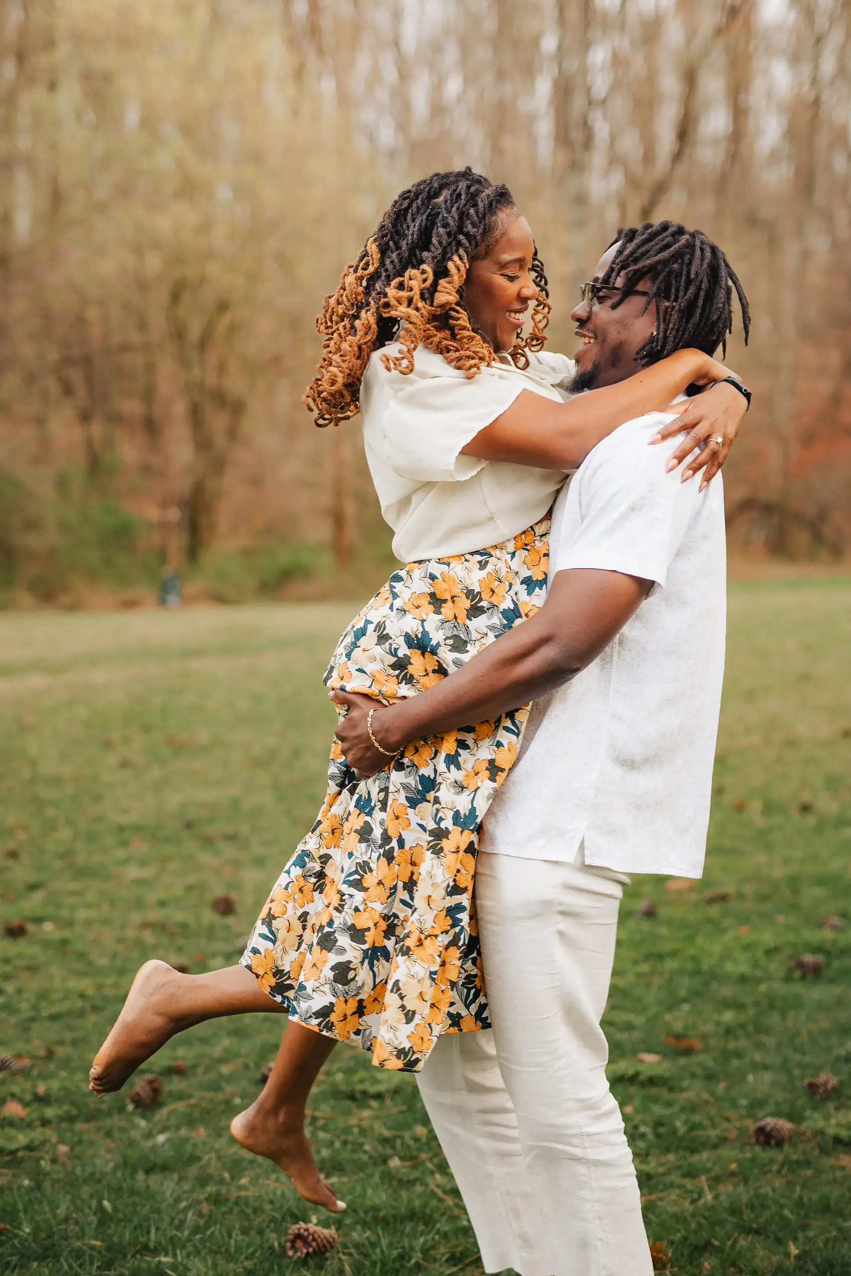Engagement Portraits: her lifted up in his arms among the bare trees, during their engagement session at Lullwater Preserve in Atlanta, GA
