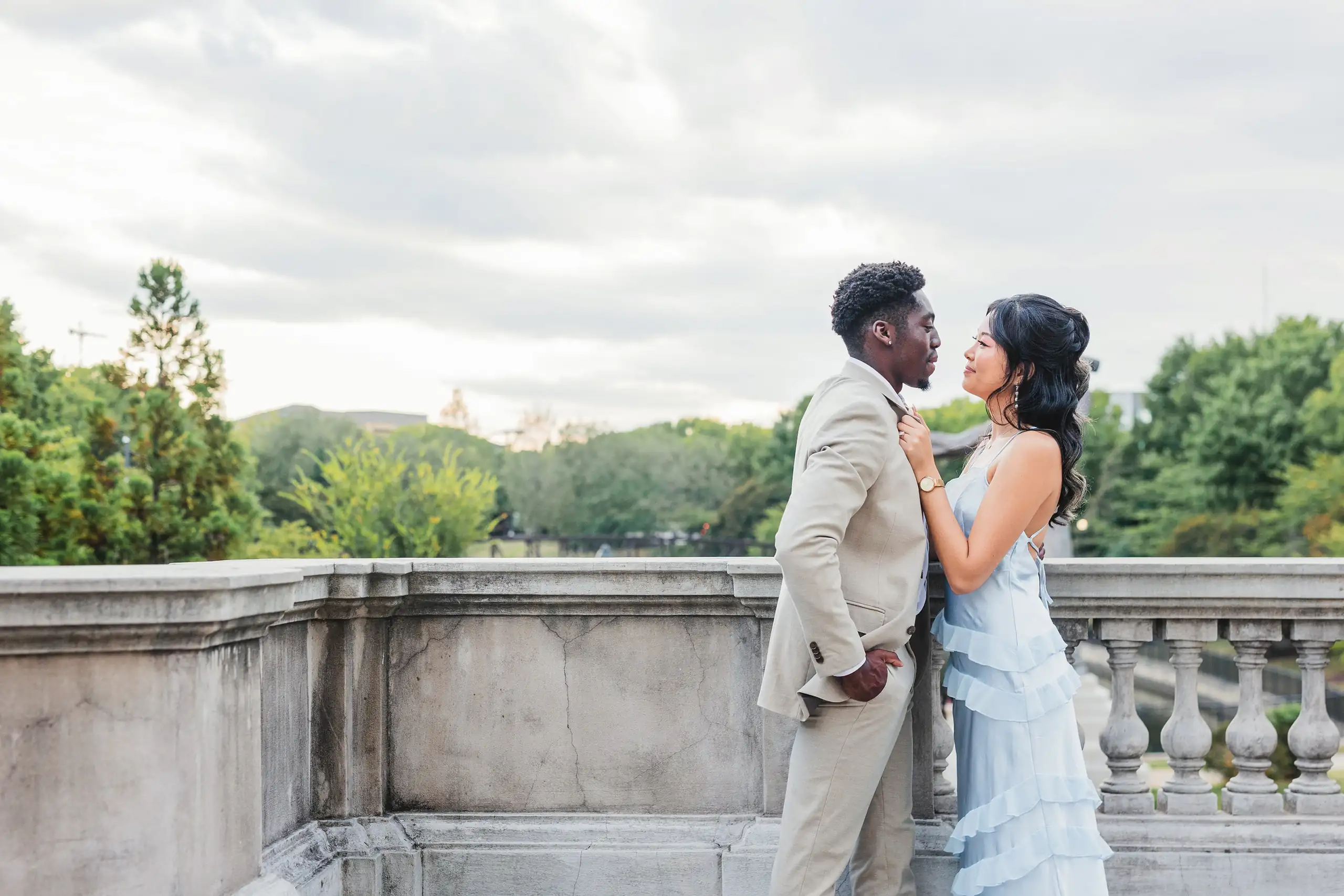 Engagement Portraits: the couple against the stone balustrade above the trees, during their engagement session at the Millennium Gate in Atlanta, GA