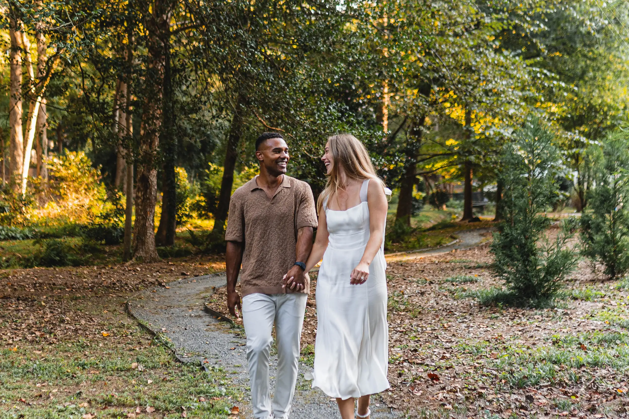 Engagement Portraits: the couple in white and brown on the wooded path, during their engagement session