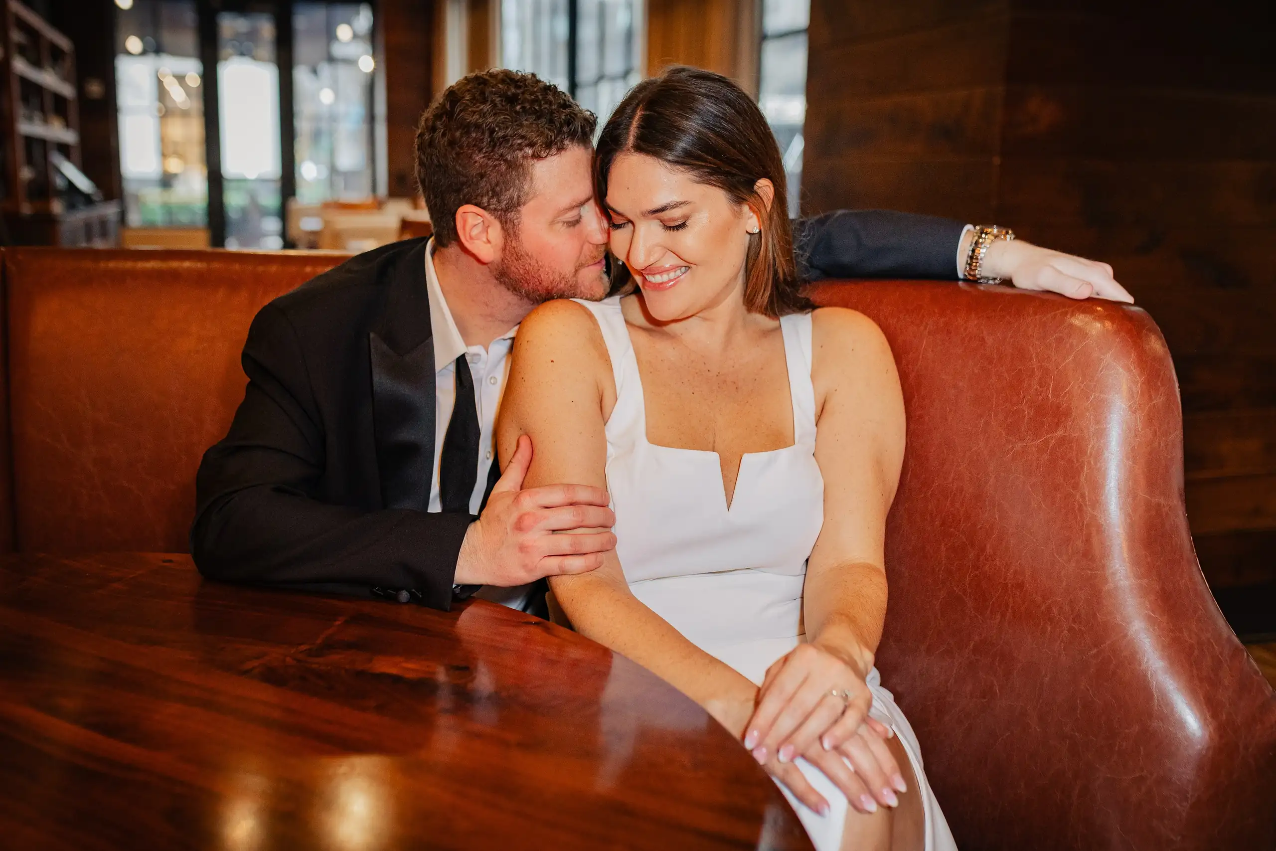 Engagement Portraits: the two of them in the leather booth downstairs, during their engagement session at the Hotel at Avalon in Alpharetta, GA