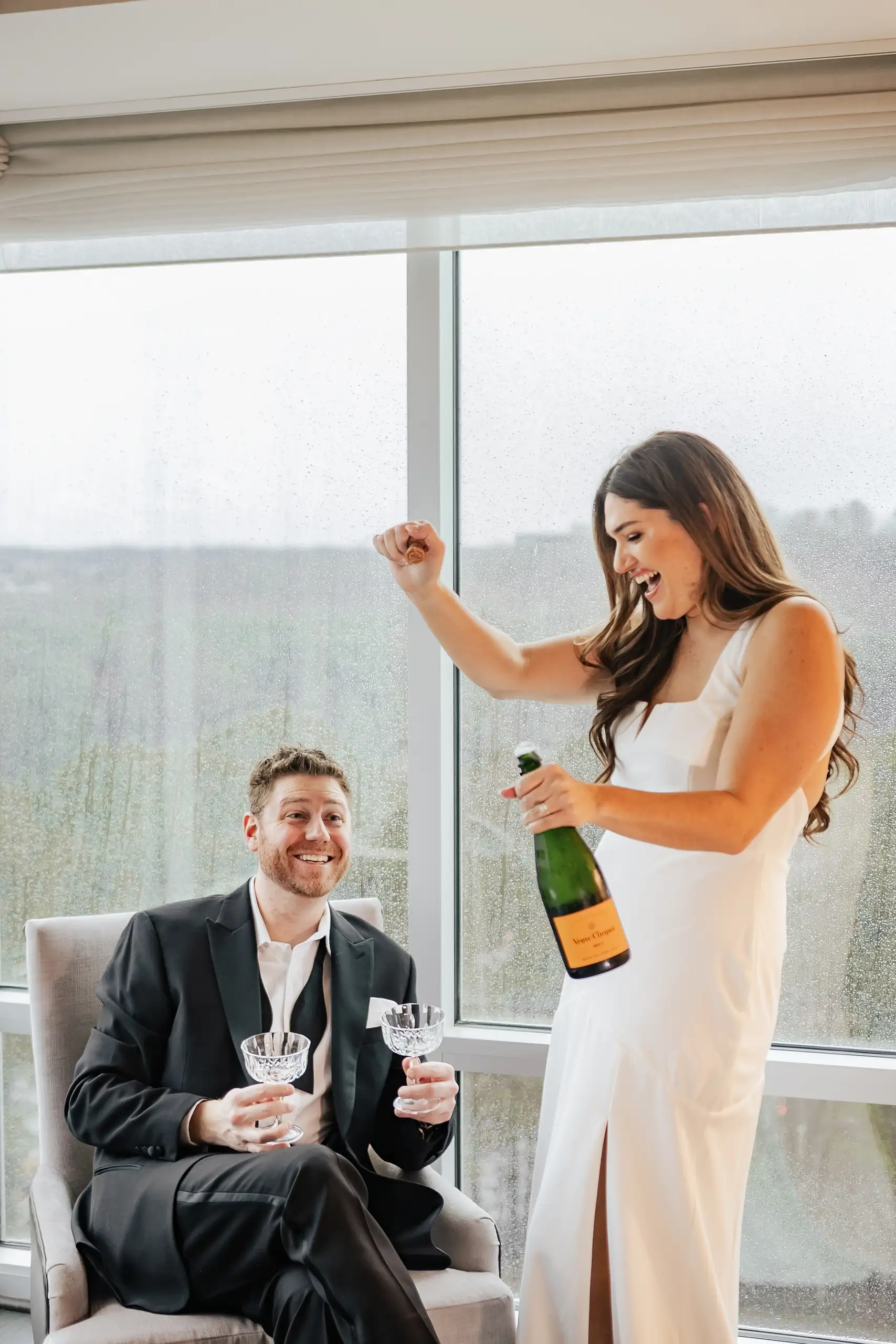 Engagement Portraits: her opening champagne in the hotel suite, during their engagement session at the Hotel at Avalon in Alpharetta, GA