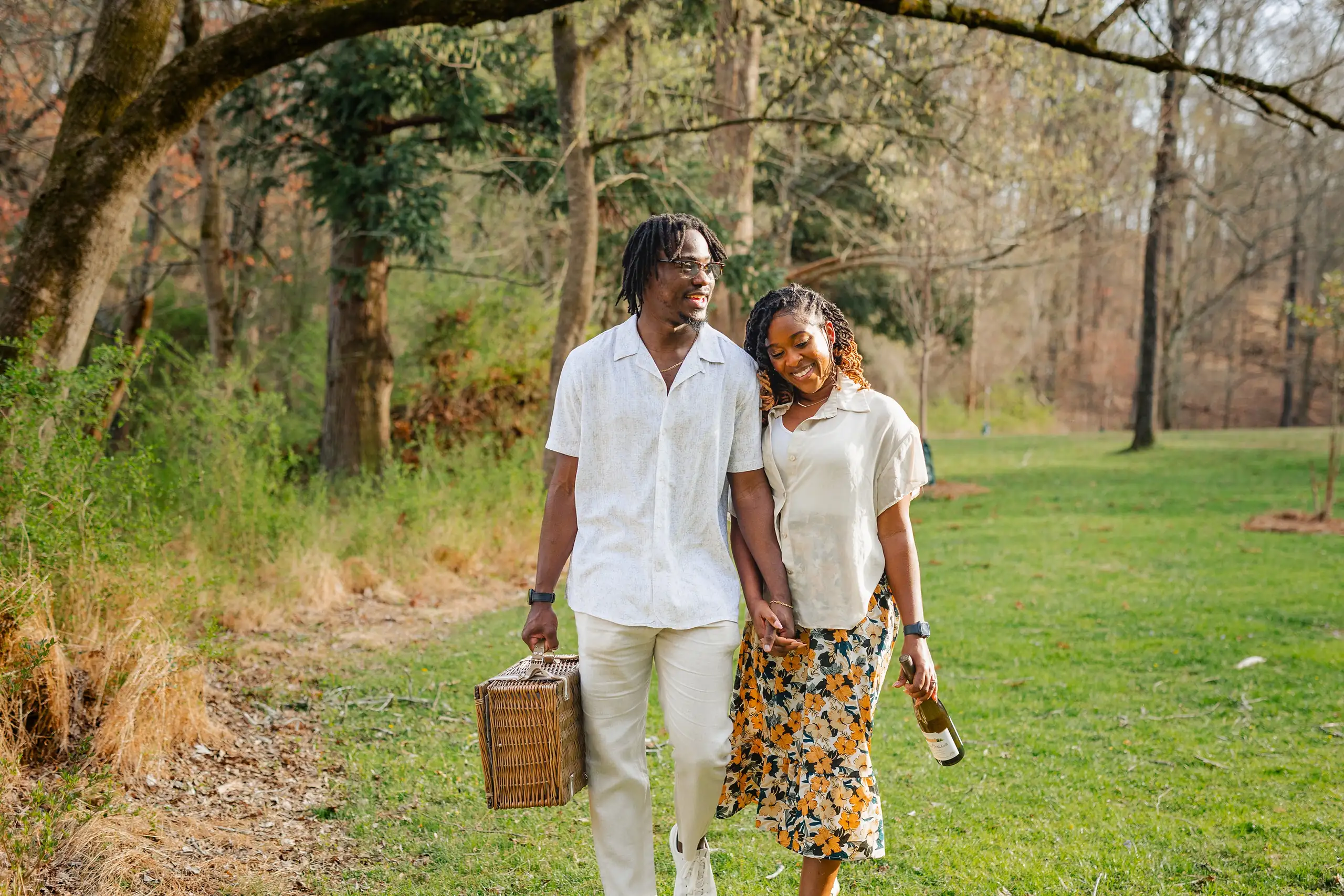 Engagement Portraits: the two of them walking the meadow with a picnic basket, during their engagement session at Lullwater Preserve in Atlanta, GA