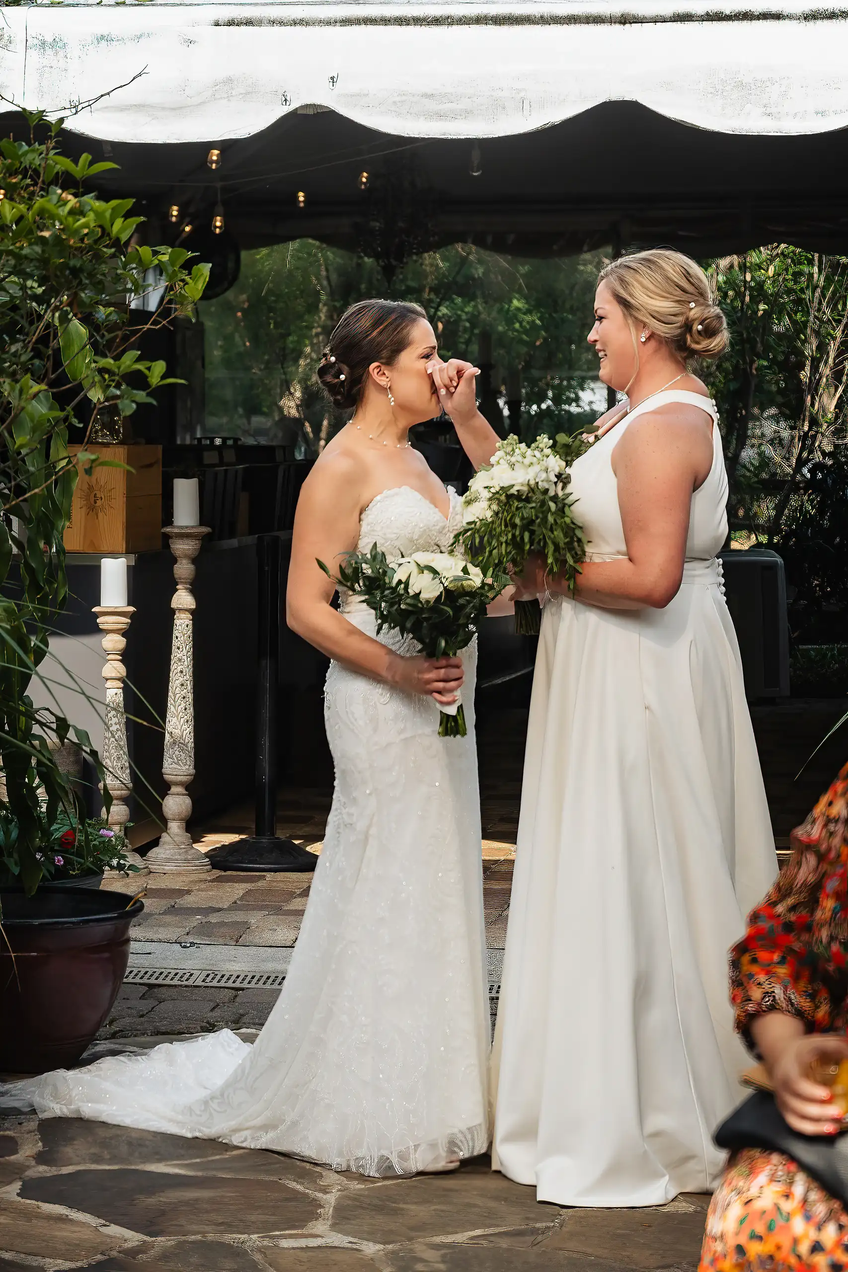 Wedding Ceremony: two brides facing each other with their bouquets, at their wedding at Wahoo! Grill in Decatur, GA