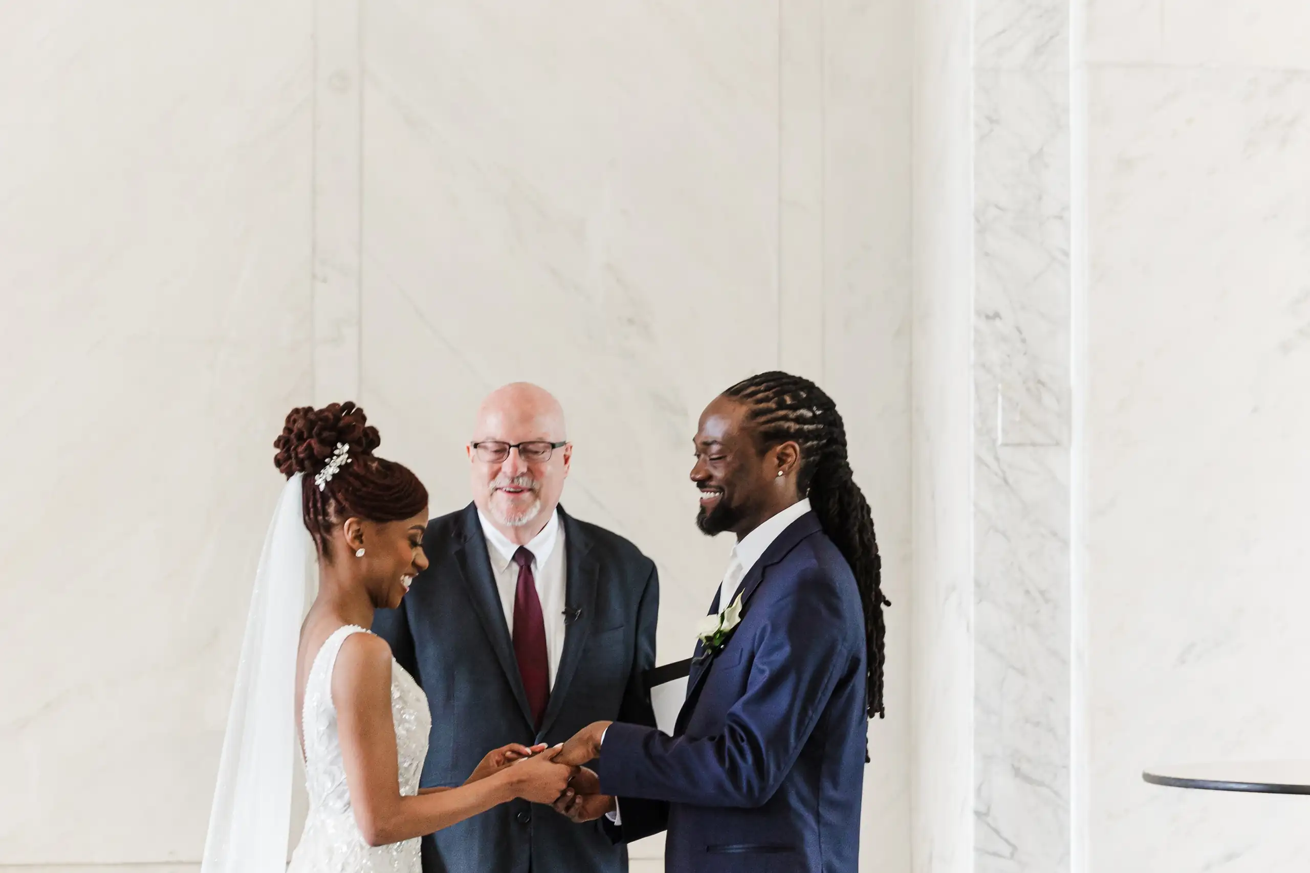 Wedding Ceremony: the vows before the officiant in the marble hall, at their wedding at Decatur Square in Decatur, GA