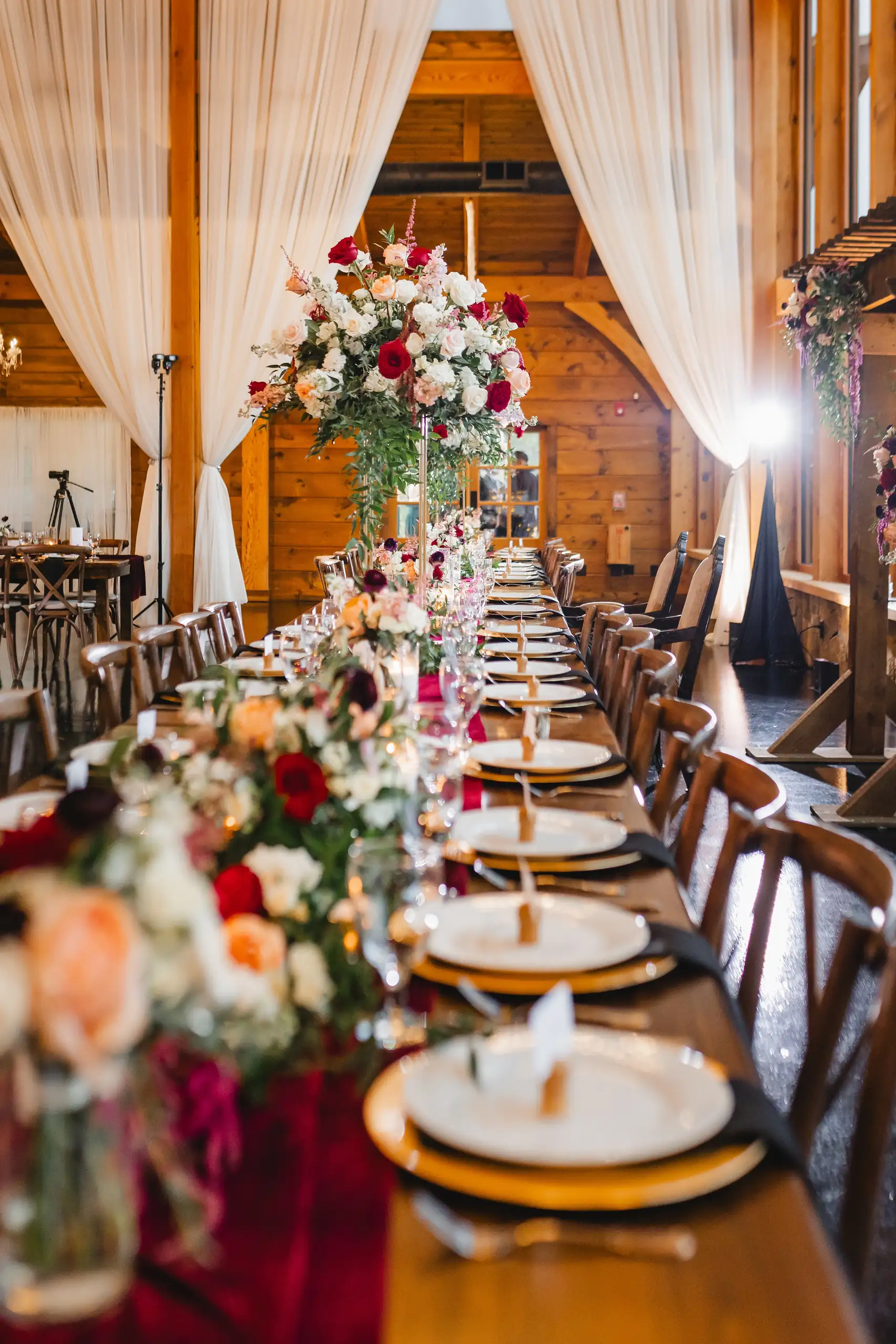 Reception Details: the long table run with red and blush flowers, at a wedding at The Venue at Sharp Mountain in Jasper, GA