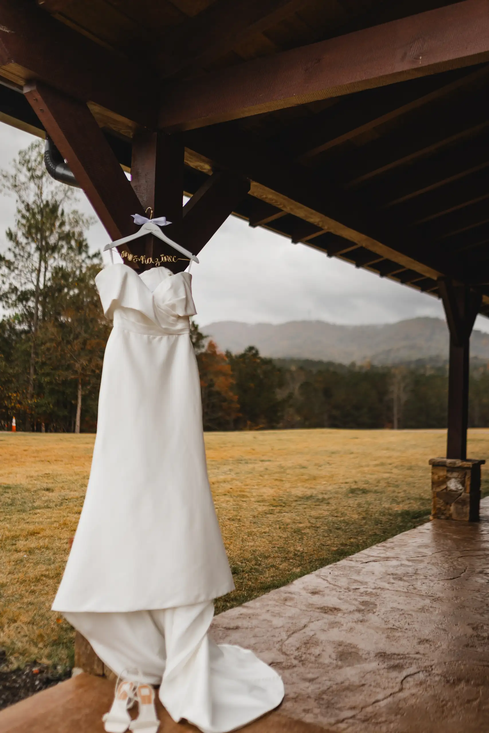 Wedding Details: the gown hanging from the timber pavilion, at a wedding at The Venue at Sharp Mountain in Jasper, GA