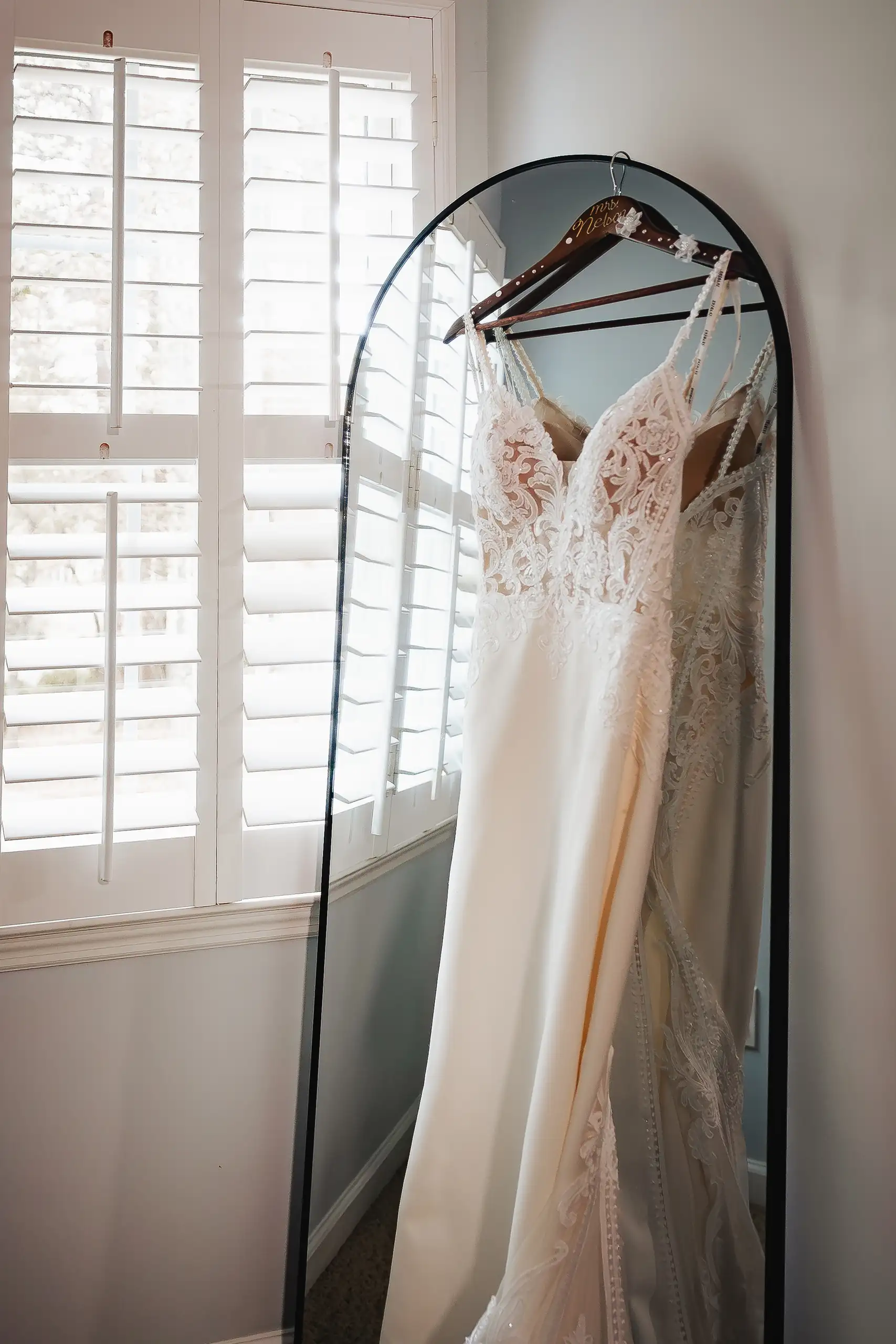 Wedding Details: the lace gown hanging in the window light, at a wedding at Swan Lake Overlook in Dawsonville, GA