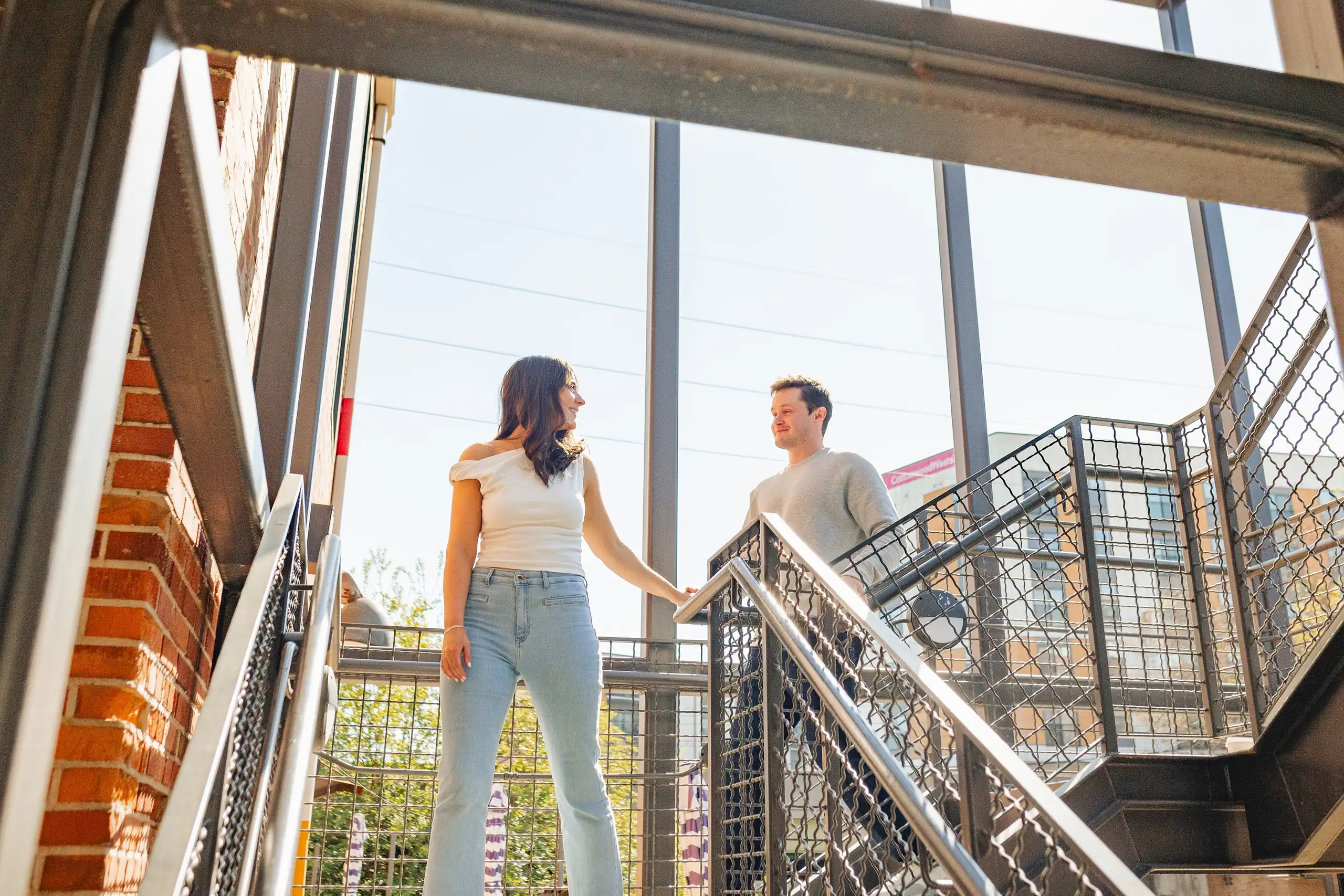 Engagement Portraits: the two of them either side of the steel staircase, during their engagement session at Westside Provisions in Atlanta, GA