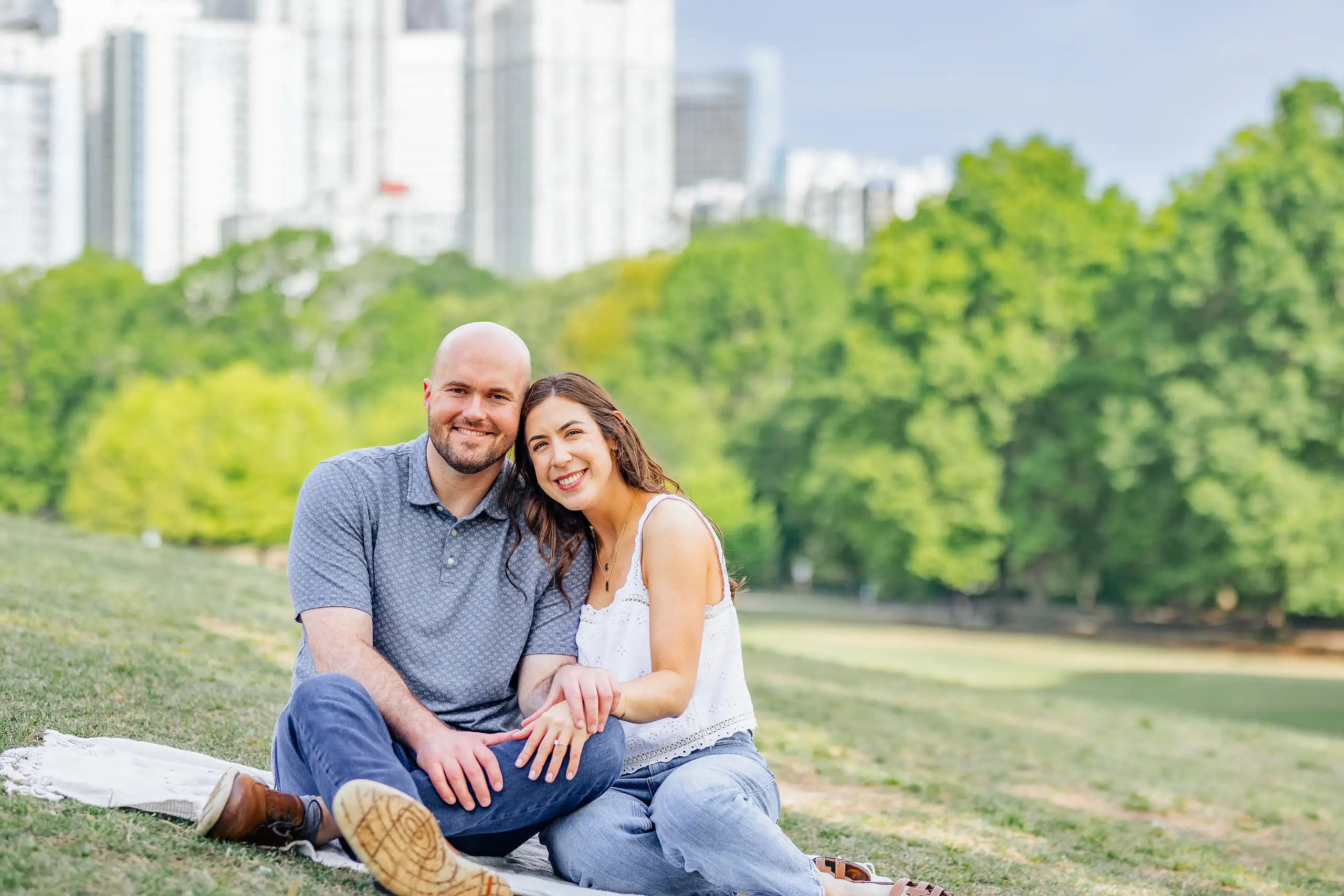 Engagement Portraits: the couple sitting together on the park lawn, during their engagement session at Piedmont Park in Atlanta, GA