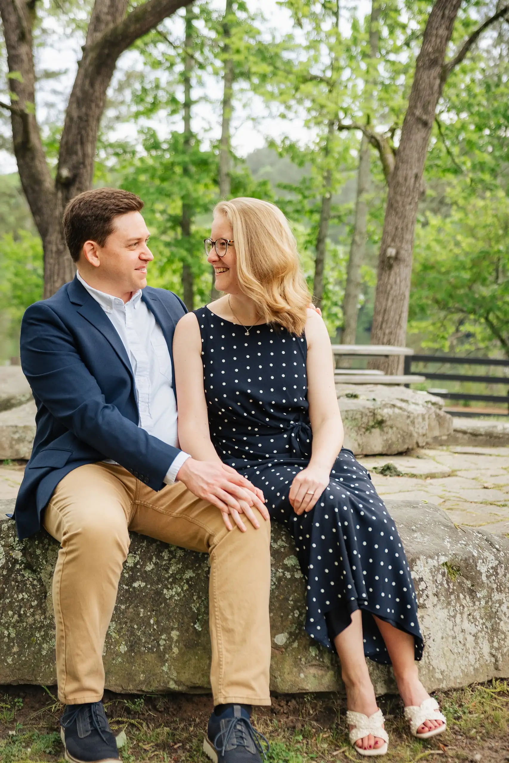 Engagement Portraits: the couple sitting on the rock in navy and khaki, during their engagement session at Sims Lake Park in Suwanee, GA