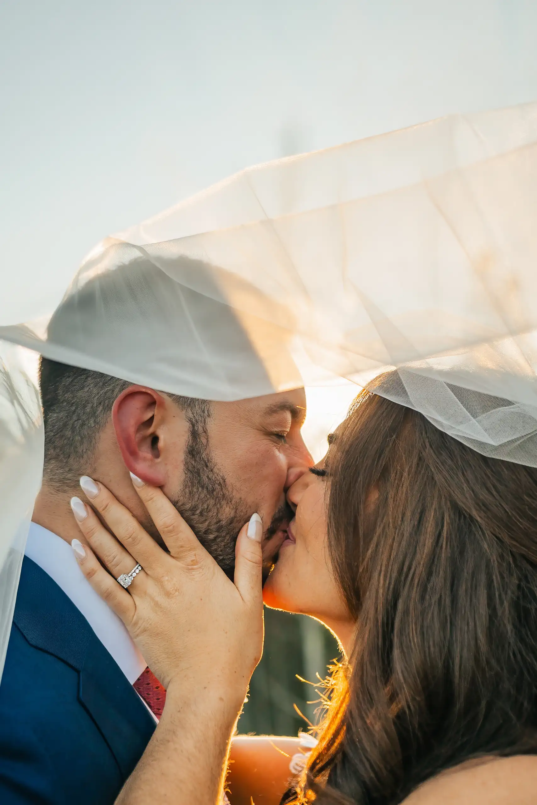 Wedding Formals: a kiss under the veil with the sun behind them, at their wedding at The Venue at Sharp Mountain in Jasper, GA