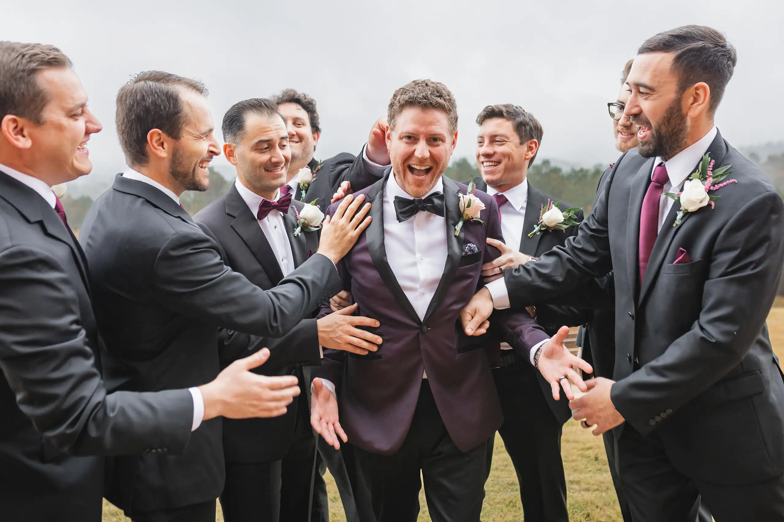 Wedding Party: the groomsmen crowding round him, all laughing, at their wedding at The Venue at Sharp Mountain in Jasper, GA
