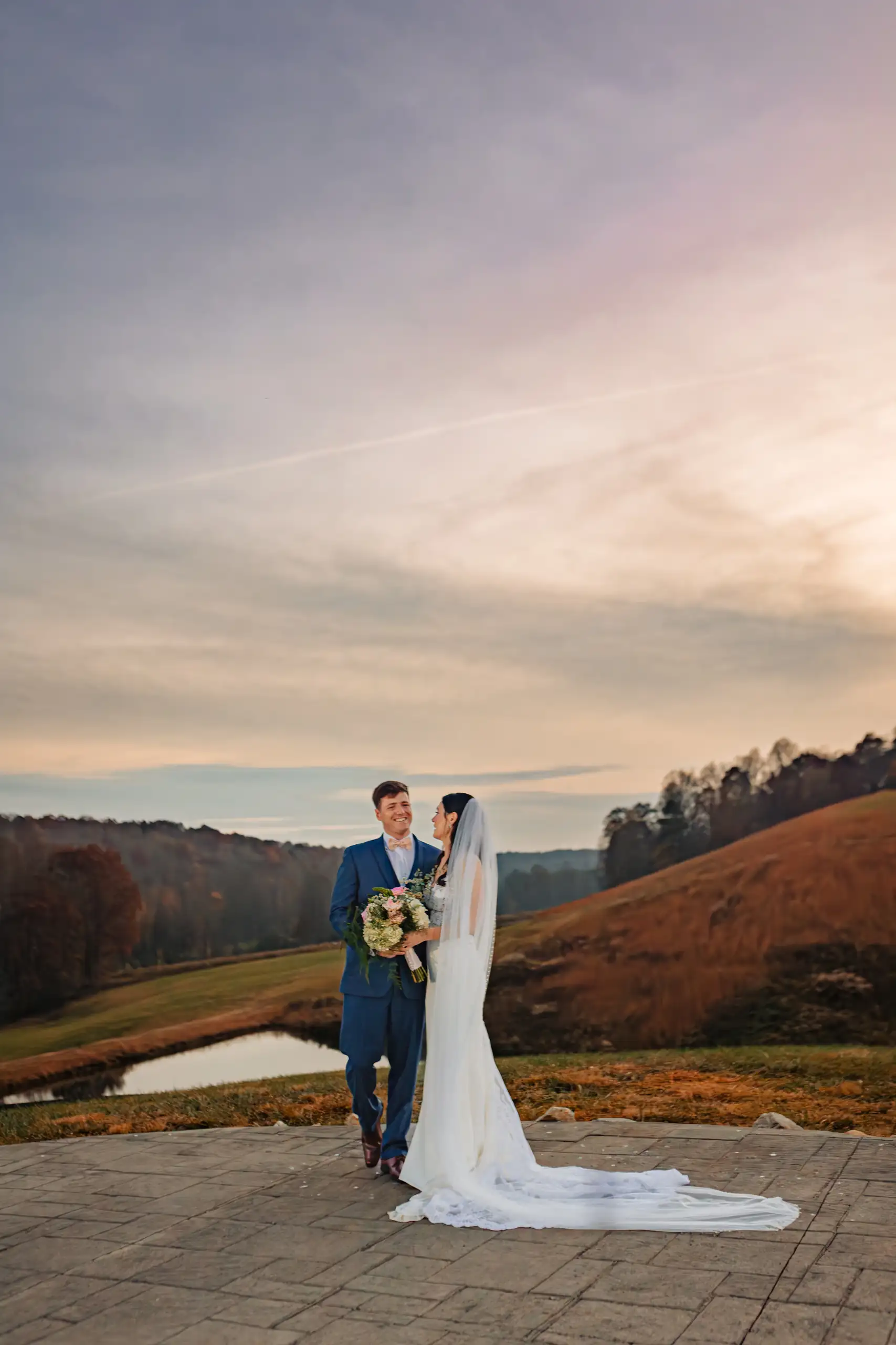 Wedding Formals: the couple small on the terrace under a wide sky, at their wedding at Swan Lake Overlook in Dawsonville, GA