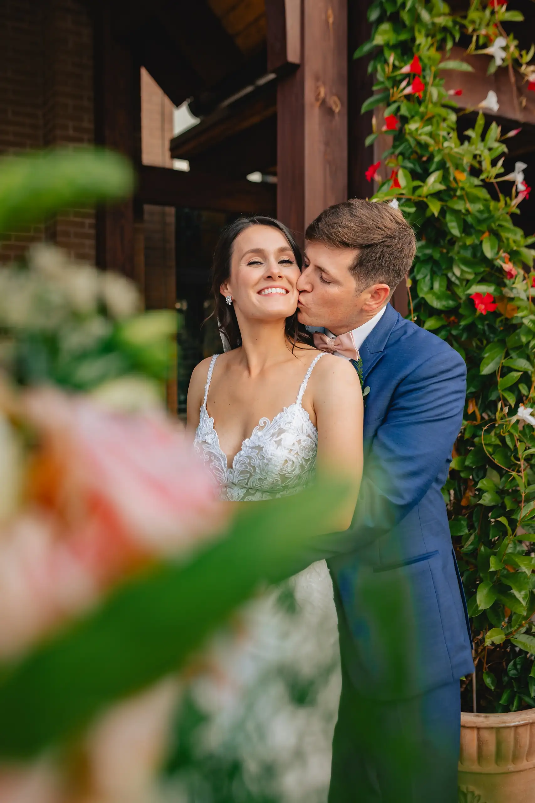 Wedding Formals: a kiss on the cheek framed by the greenery, at their wedding at Swan Lake Overlook in Dawsonville, GA