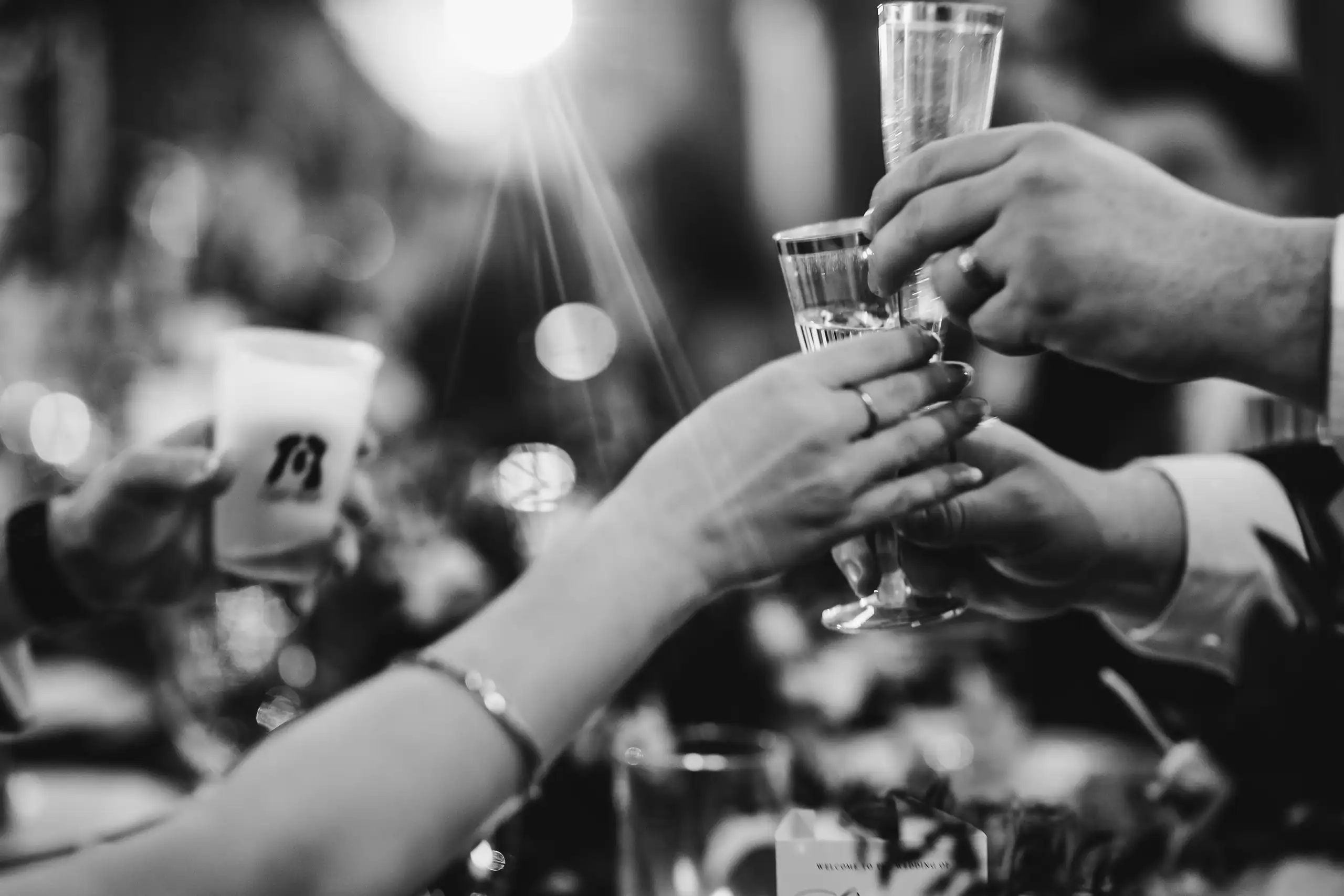 Wedding Reception: glasses meeting over the table, in black and white, at their wedding at The Venue at Sharp Mountain in Jasper, GA
