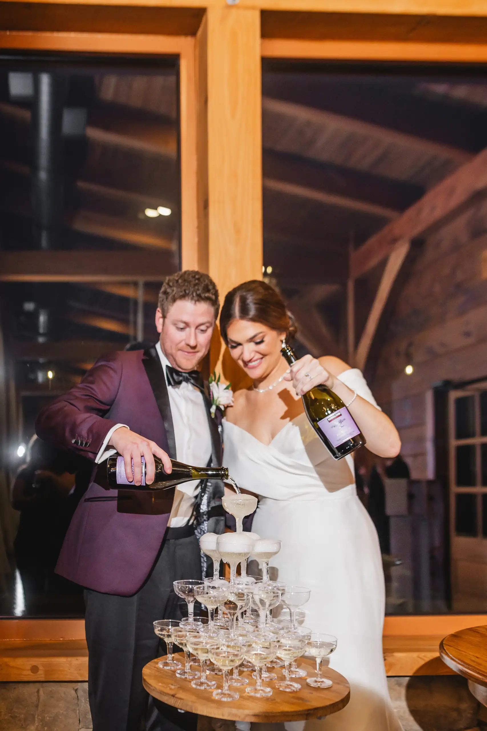 Reception Details: the couple pouring champagne down the tower of glasses, at their wedding at The Venue at Sharp Mountain in Jasper, GA