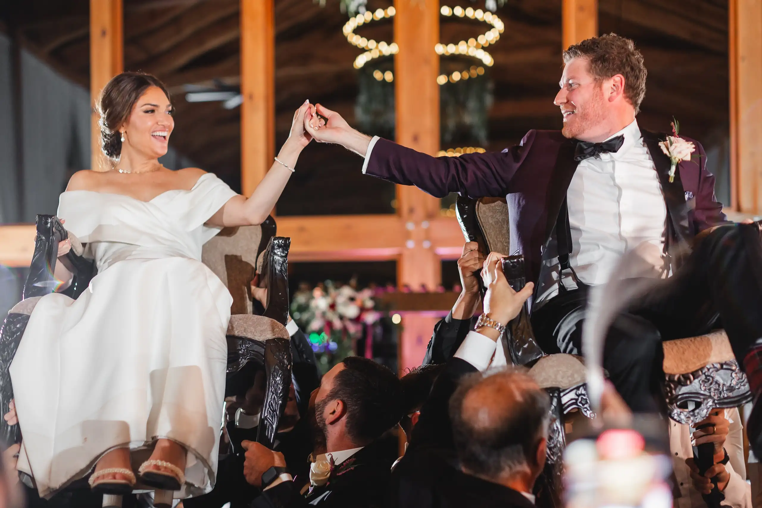 Wedding Reception: the two of them lifted up on chairs by their guests, at their wedding at The Venue at Sharp Mountain in Jasper, GA