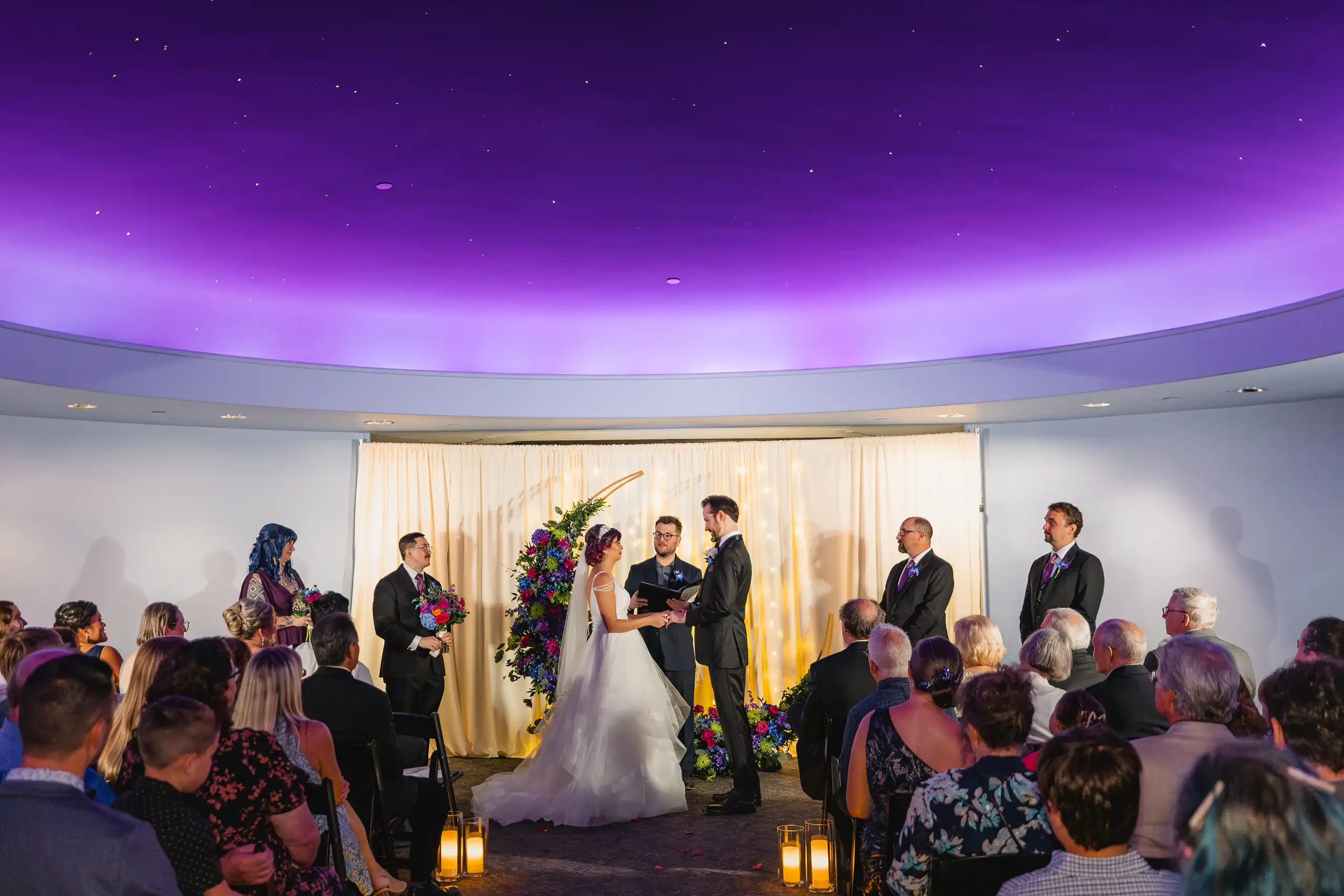 Wedding Ceremony: the ceremony under the purple dome of the gallery, at their wedding at Fernbank Museum in Atlanta, GA