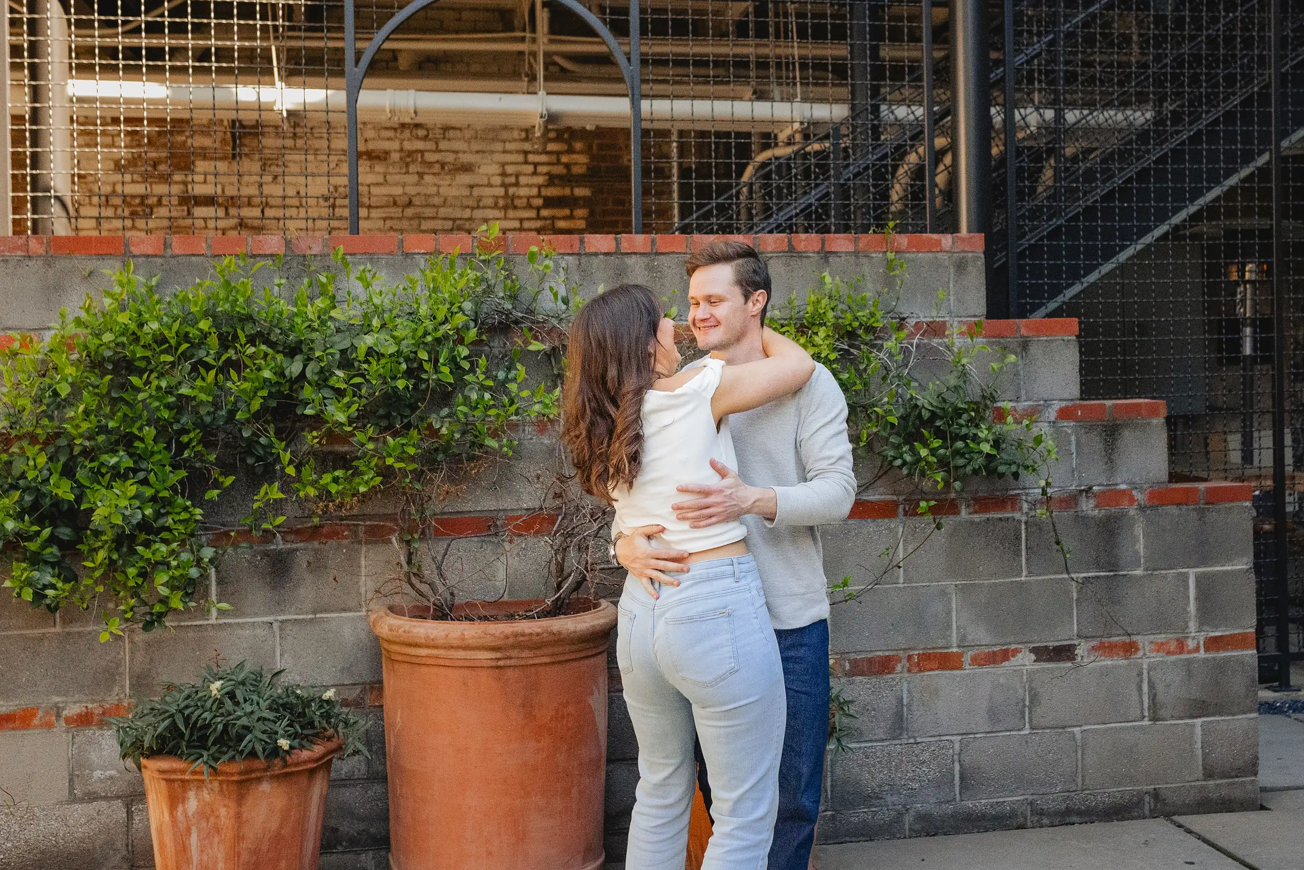 Engagement Portraits: a hug among the planters on the loading dock, during their engagement session at Westside Provisions in Atlanta, GA