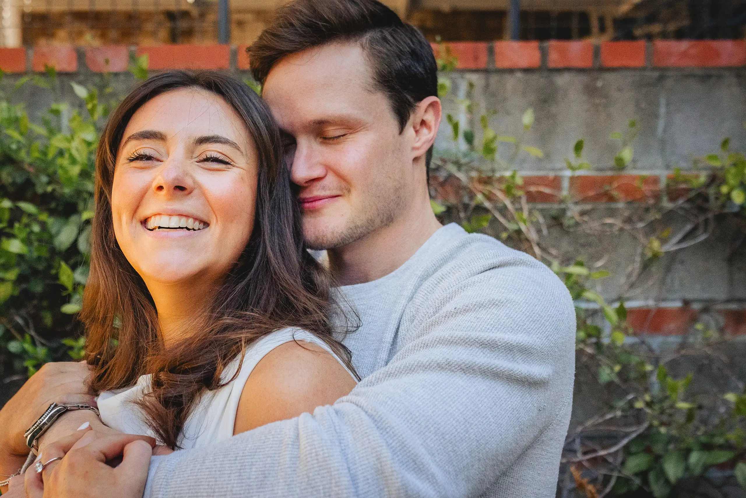 Engagement Portraits: her laughing as he holds her from behind, during their engagement session at Westside Provisions in Atlanta, GA