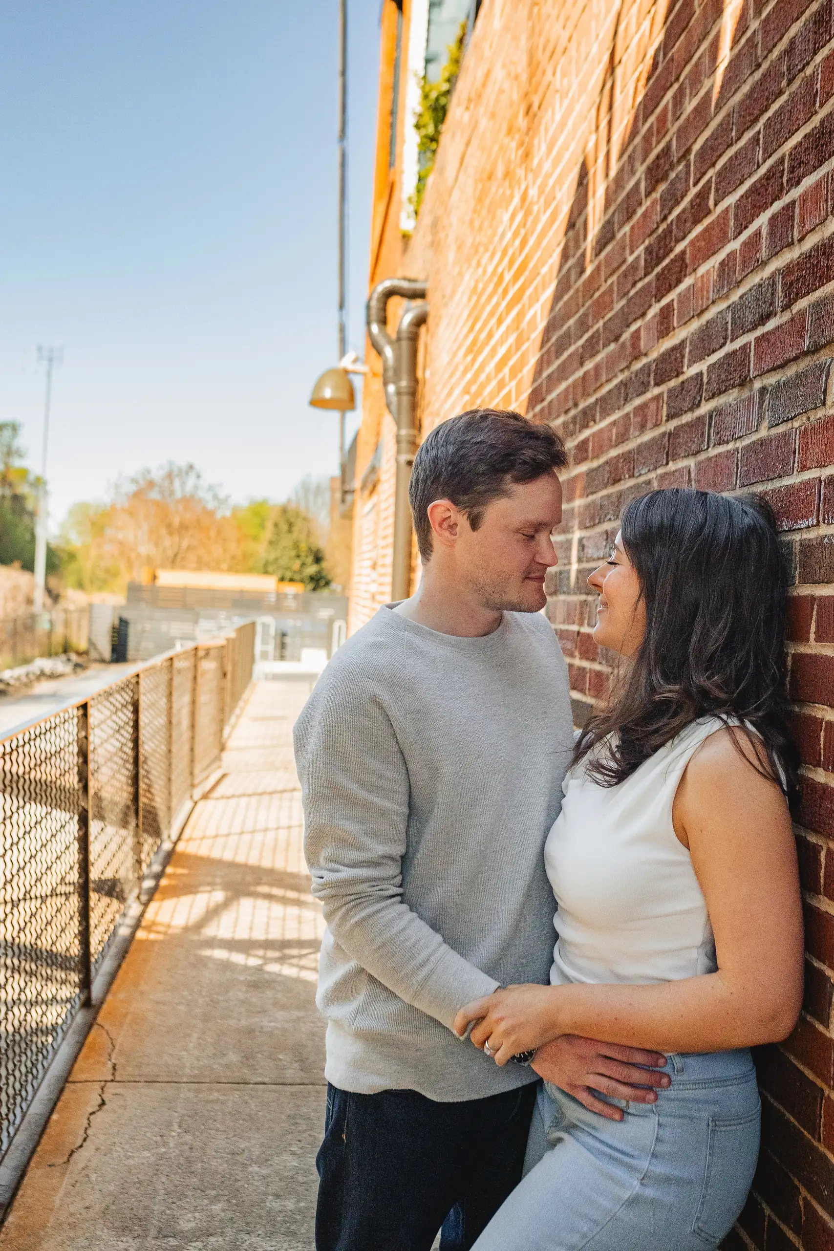 Engagement Portraits: the two of them against the brick wall in the sun, during their engagement session at Westside Provisions in Atlanta, GA