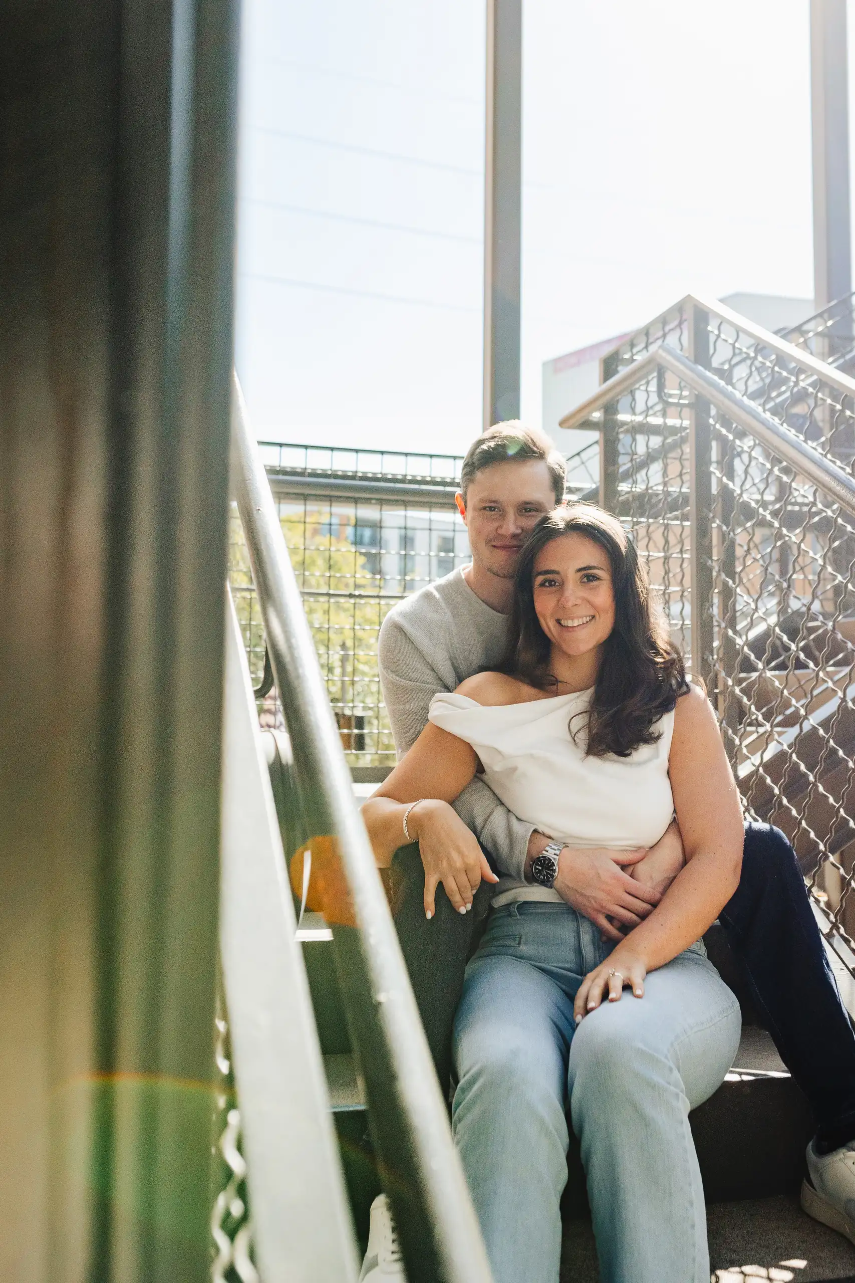 Engagement Portraits: the couple sitting together on the steel walkway, during their engagement session at Westside Provisions in Atlanta, GA