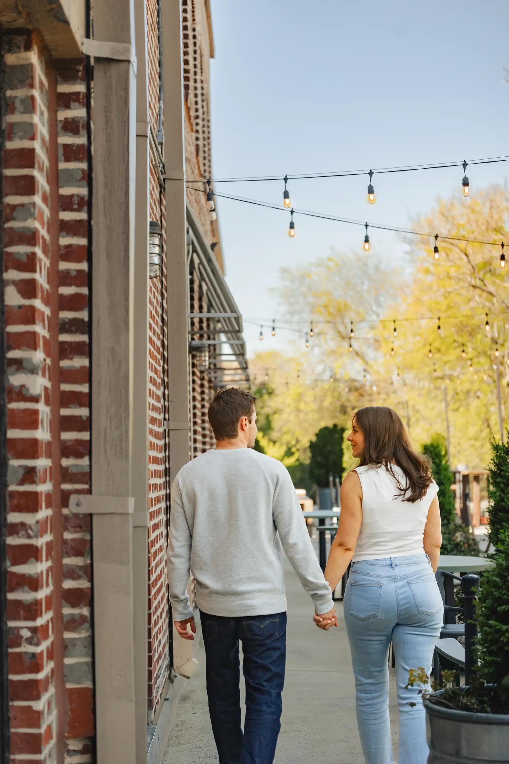 Engagement Portraits: the couple walking away hand in hand under the lights, during their engagement session at Westside Provisions in Atlanta, GA