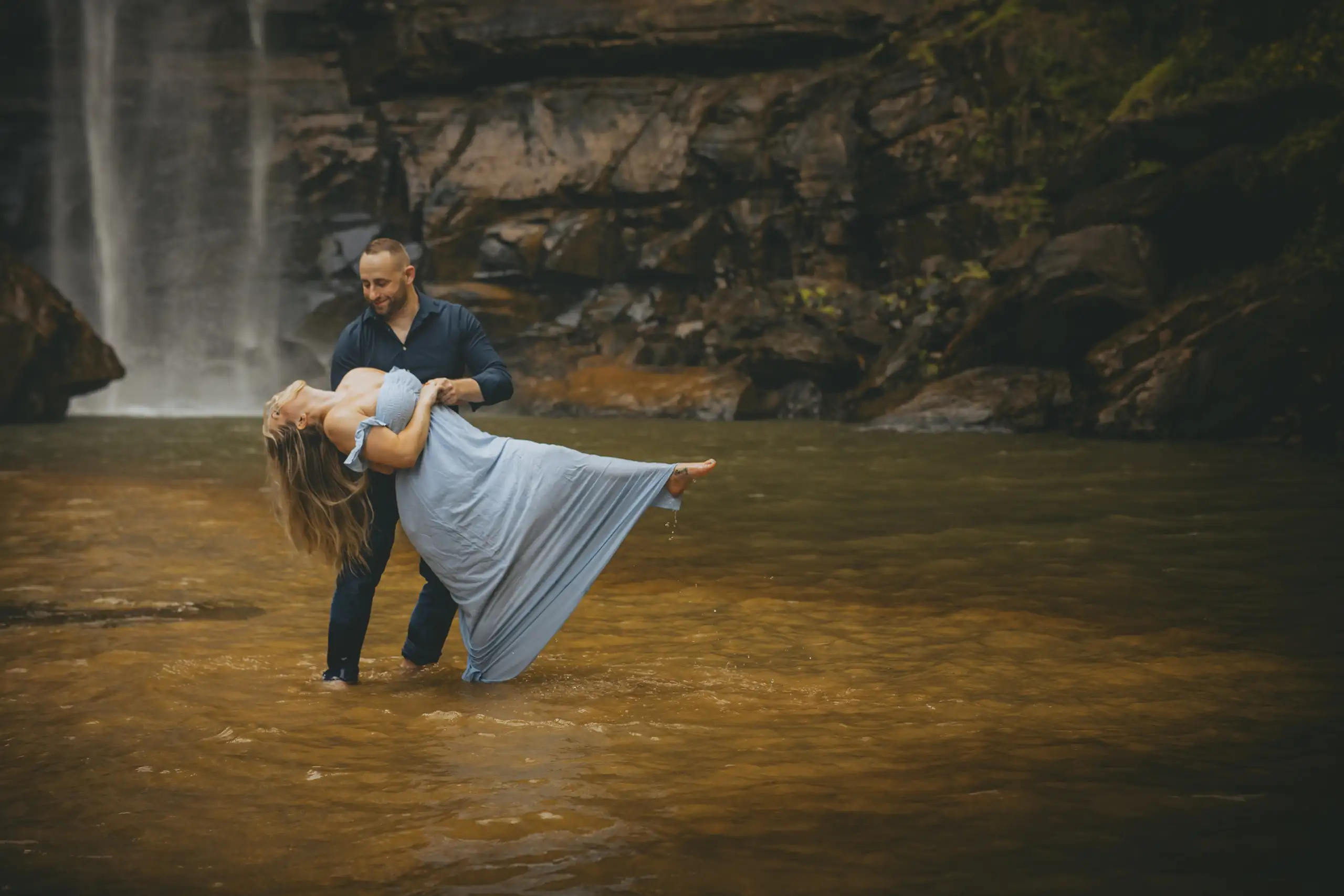 Engagement Portraits: him dipping her in the water below the falls, during their engagement session at Toccoa Falls in Toccoa, GA