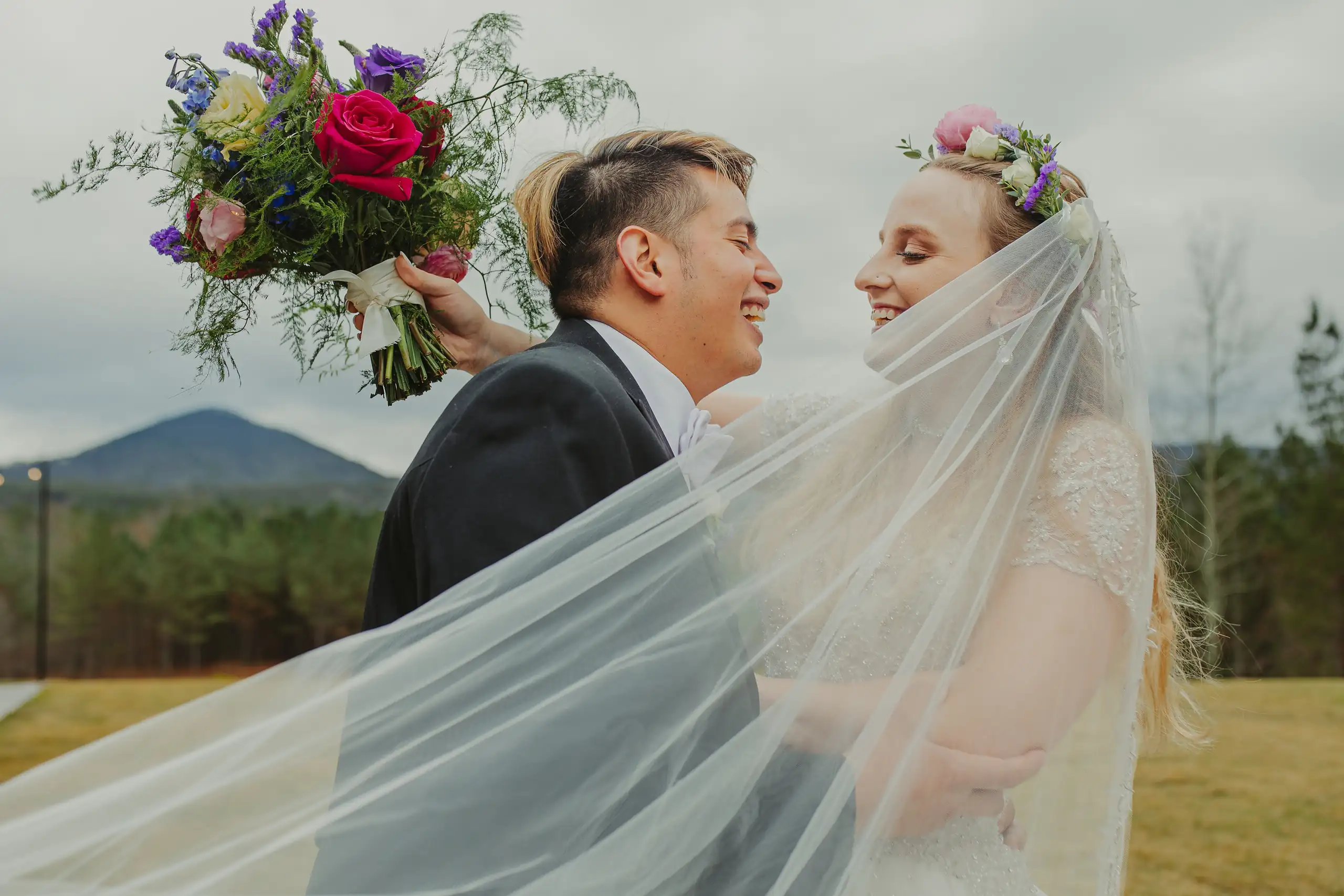 Wedding Formals: her veil blowing across them both, the ridge behind, at their wedding at The Venue at Sharp Mountain in Jasper, GA