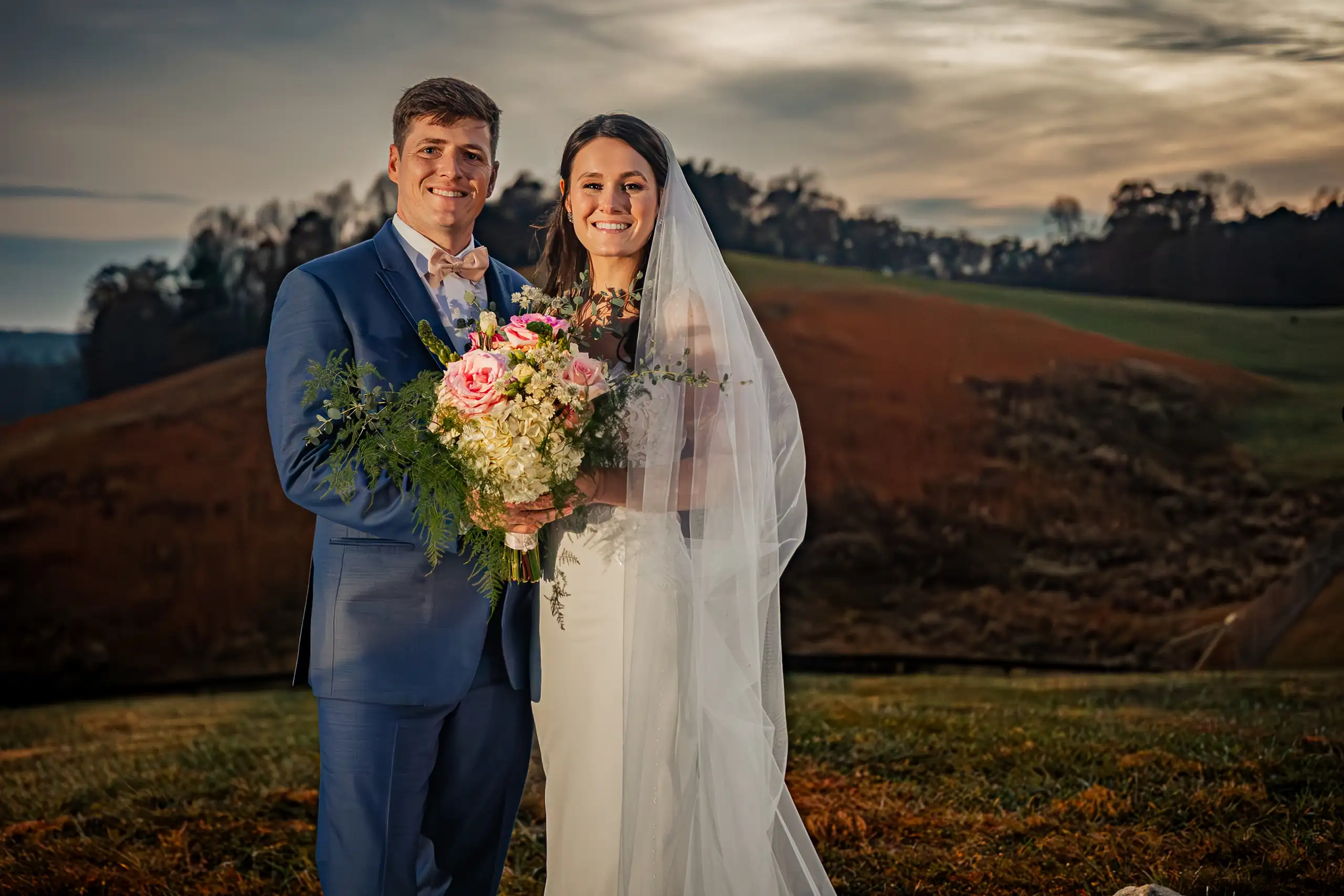 Wedding Formals: the couple with her bouquet on the hillside at dusk, at their wedding at Swan Lake Overlook in Dawsonville, GA