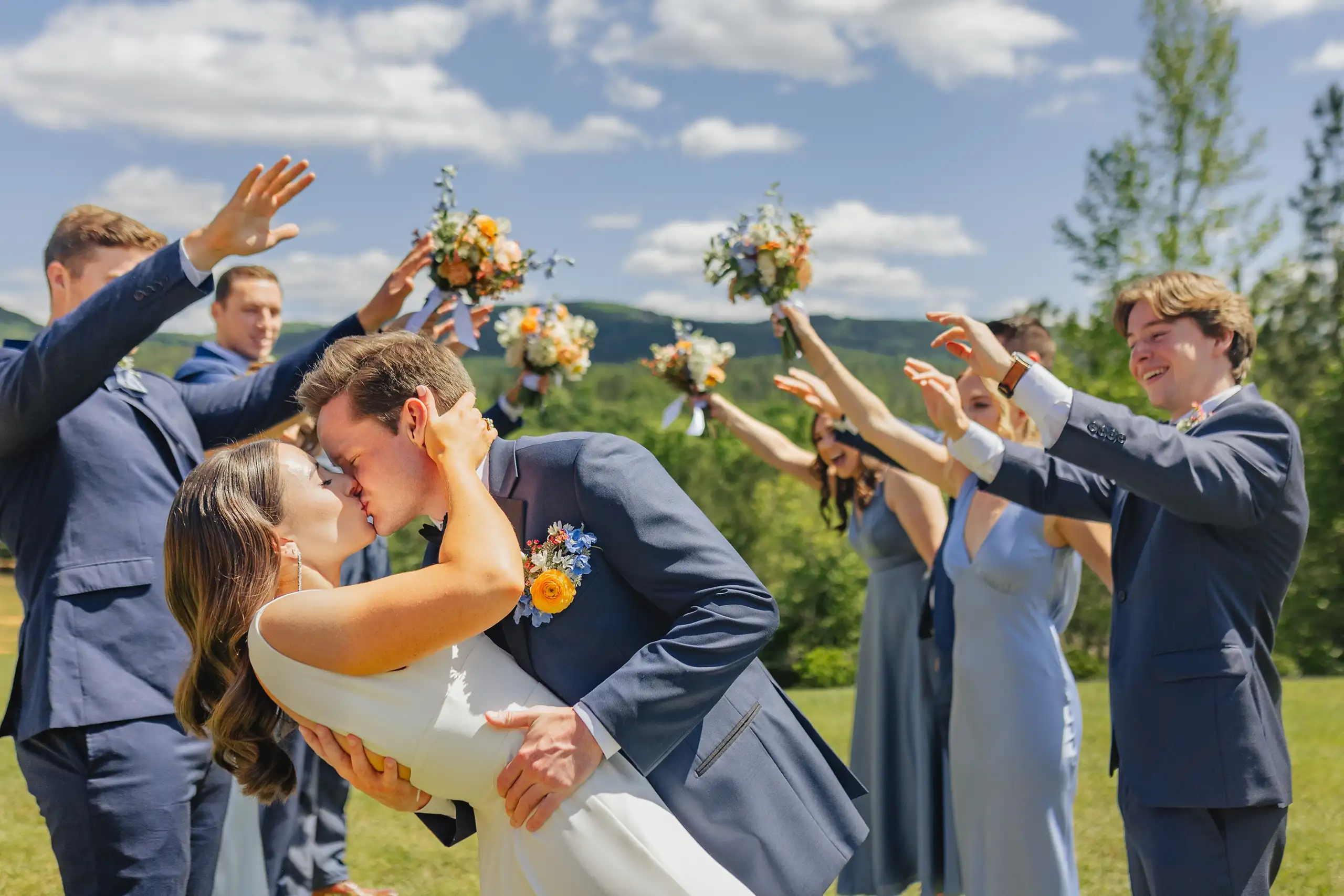 Recessional: a dip kiss as the wedding party raise their bouquets, at their wedding at The Venue at Sharp Mountain in Jasper, GA