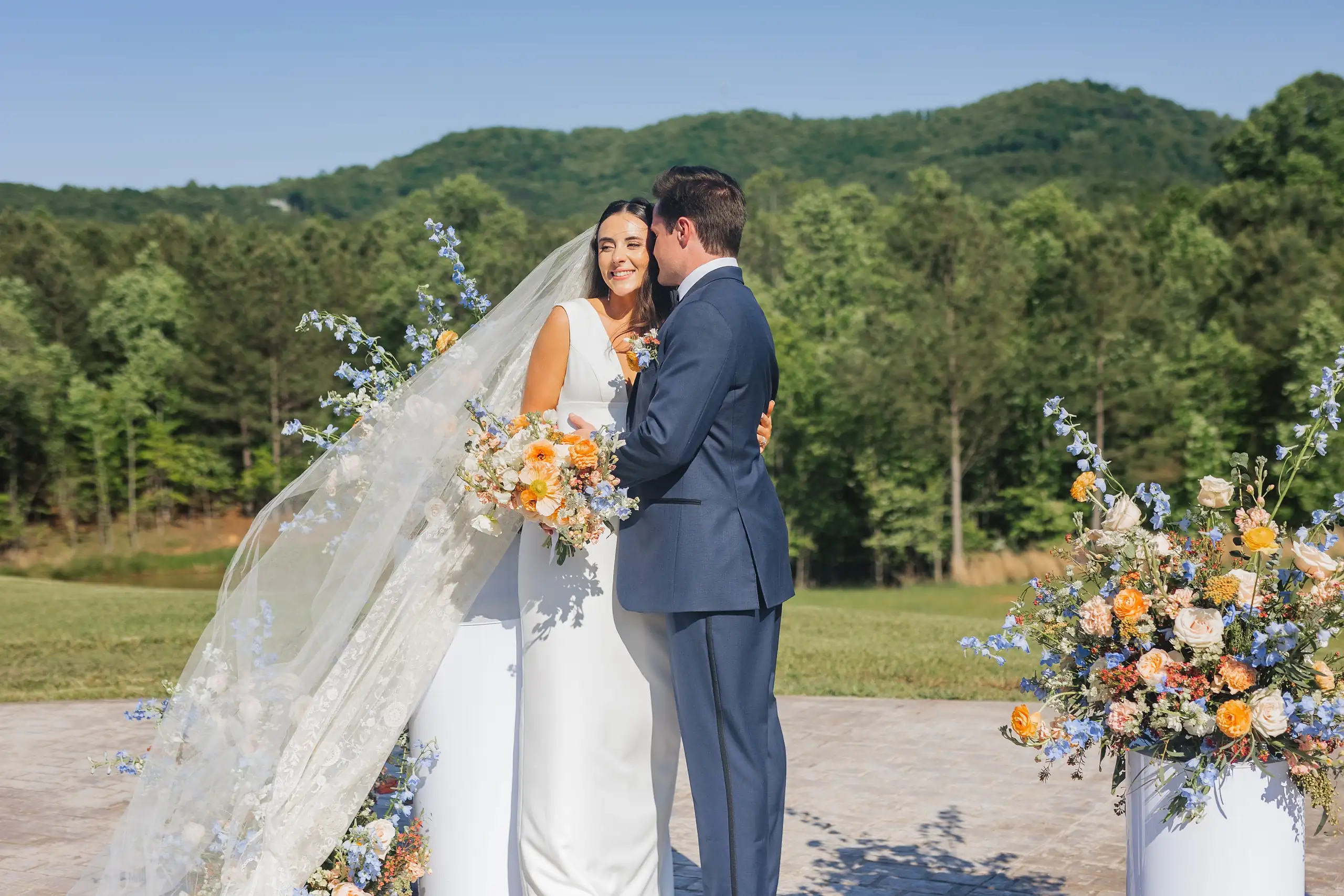 Wedding Formals: the couple by the apricot and blue florals, her veil out, at their wedding at The Venue at Sharp Mountain in Jasper, GA