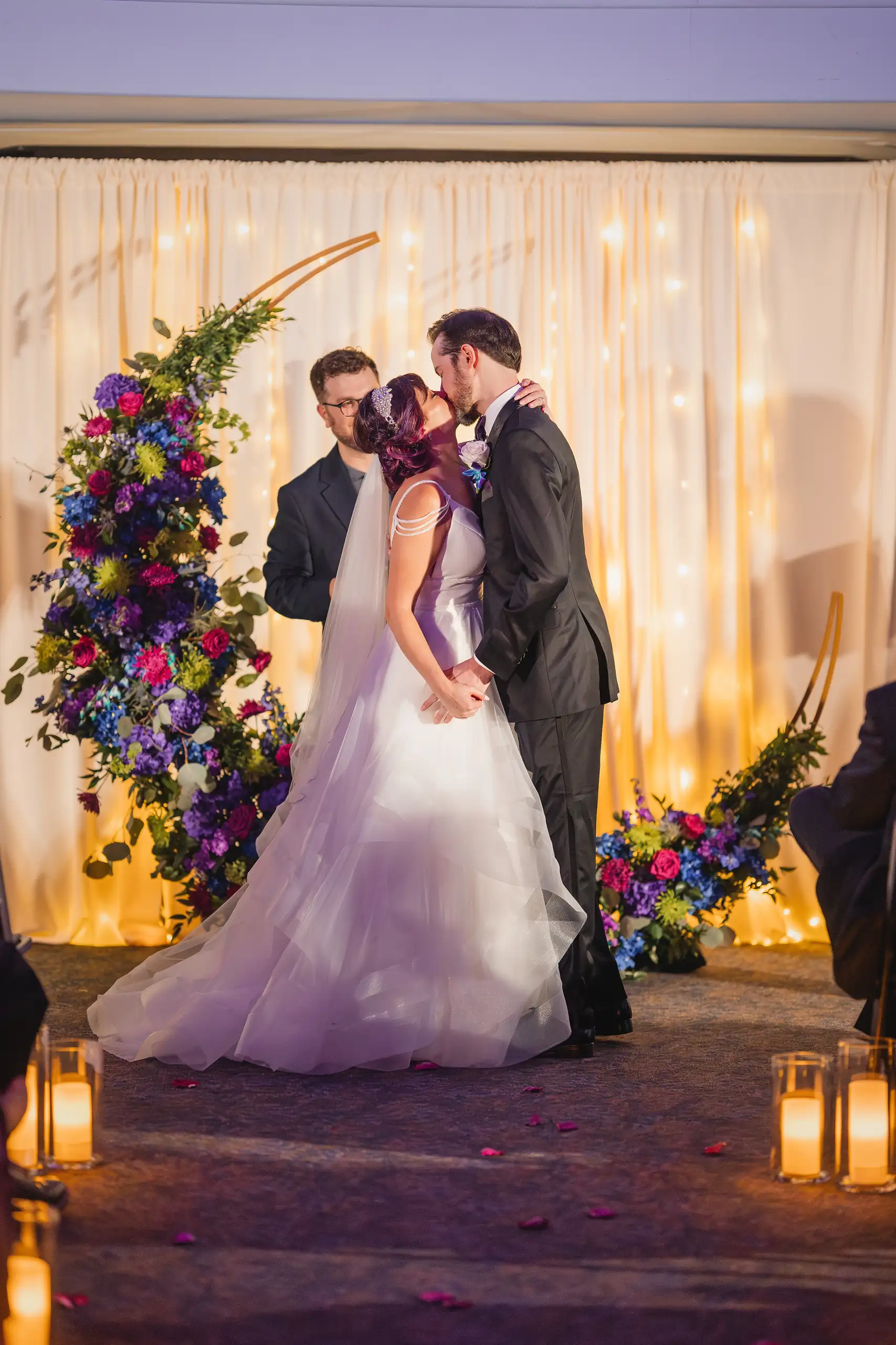 Wedding Ceremony: the first kiss beside the lanterns and the florals, at their wedding at Fernbank Museum in Atlanta, GA
