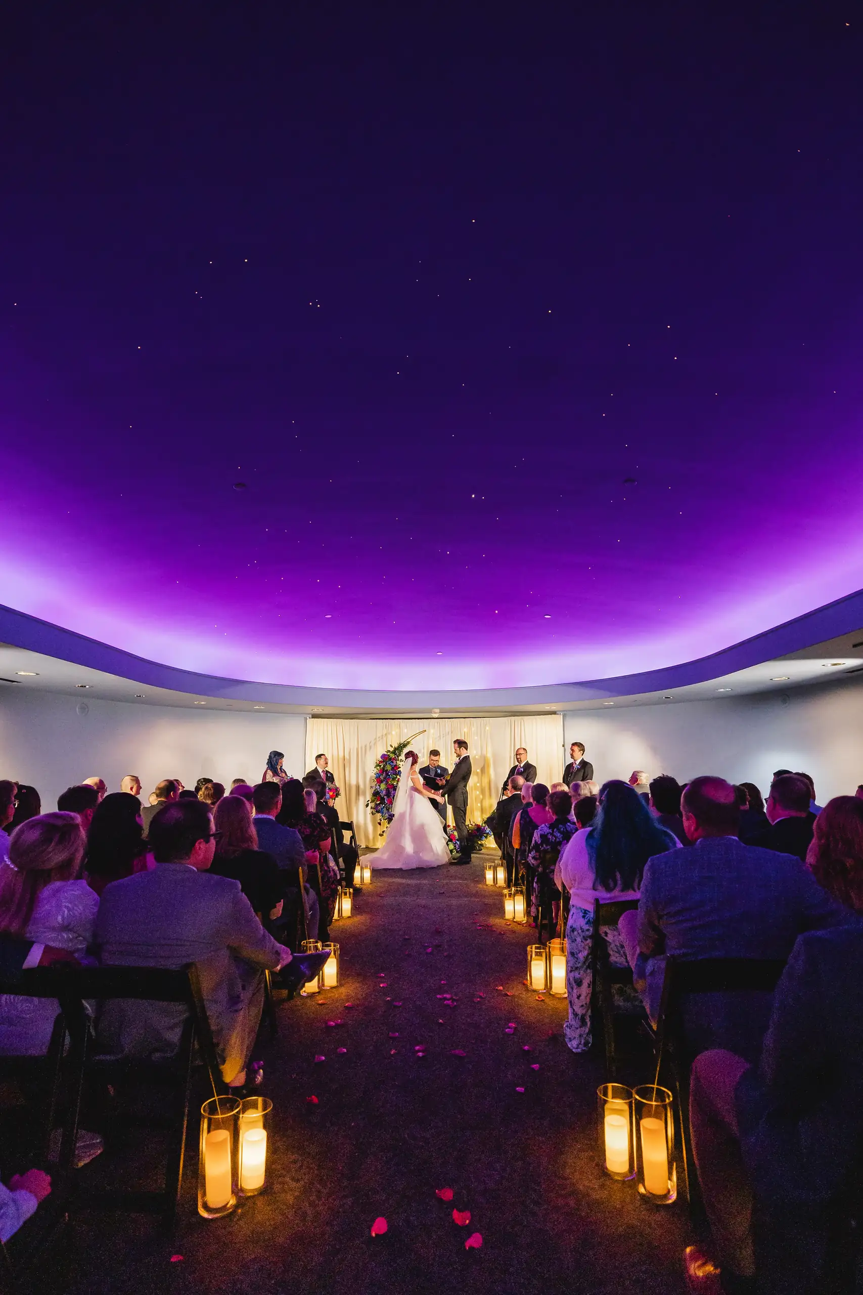 Wedding Ceremony: the aisle lined with lanterns under the domed light, at their wedding at Fernbank Museum in Atlanta, GA