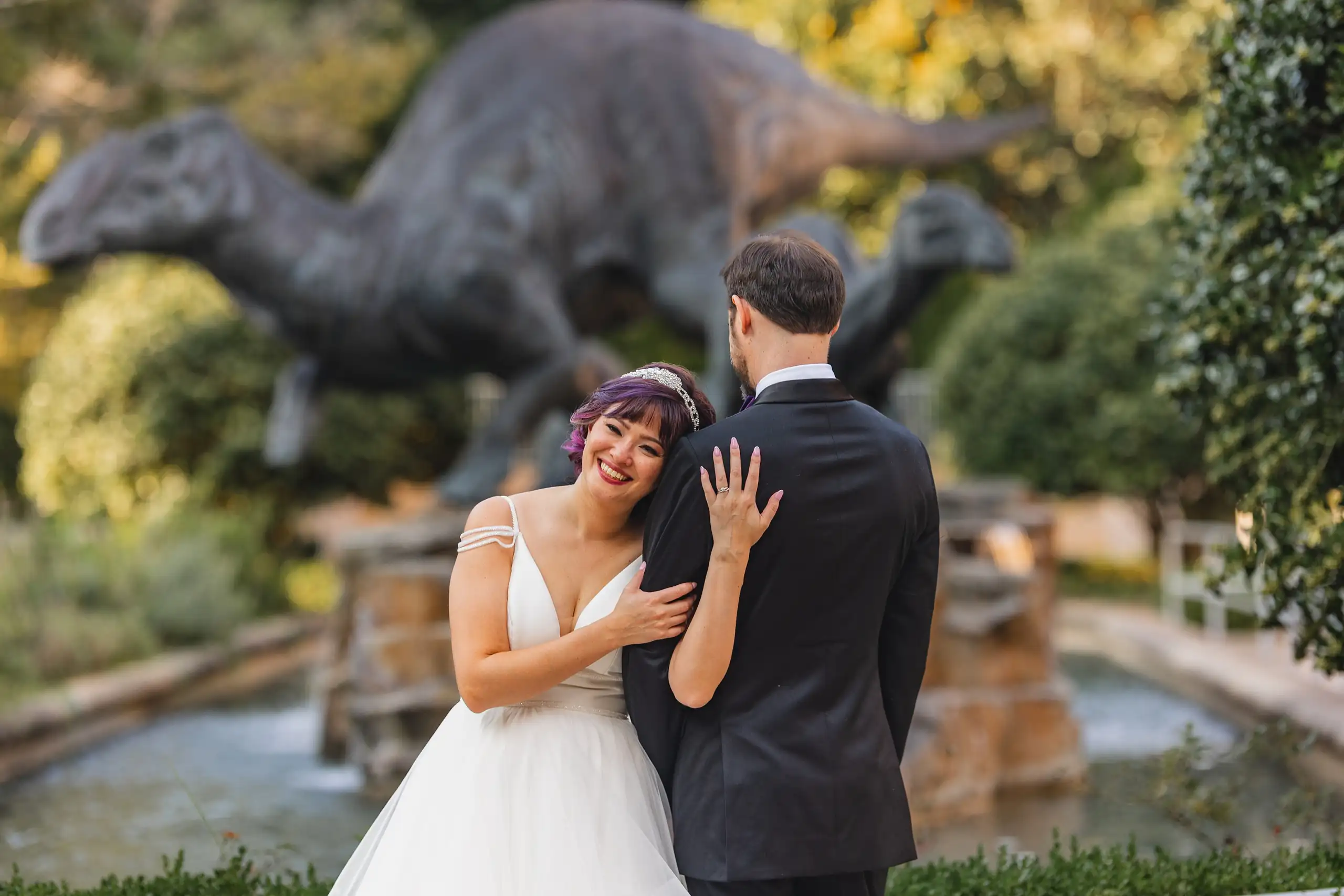 Wedding Formals: the couple by the fountain among the garden dinosaurs, at their wedding at Fernbank Museum in Atlanta, GA