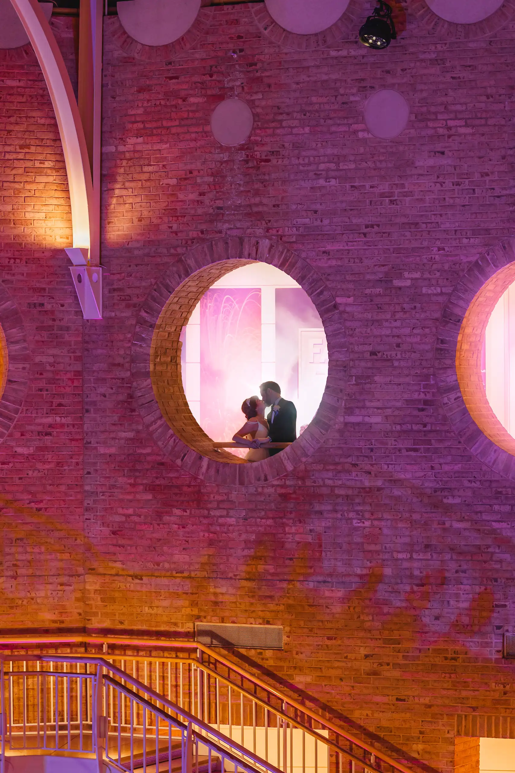 Wedding Formals: the couple framed in a round window above the stairs, at their wedding at Fernbank Museum in Atlanta, GA