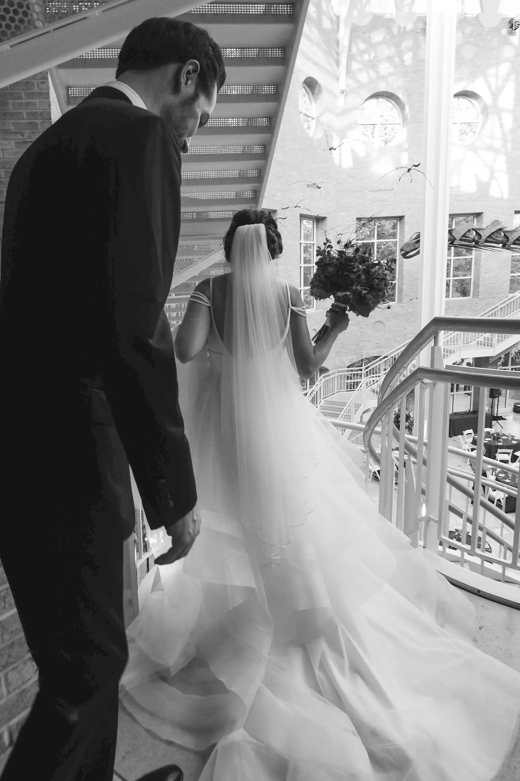 Wedding Formals: the groom leading her by the hand, in black and white, at their wedding at Fernbank Museum in Atlanta, GA