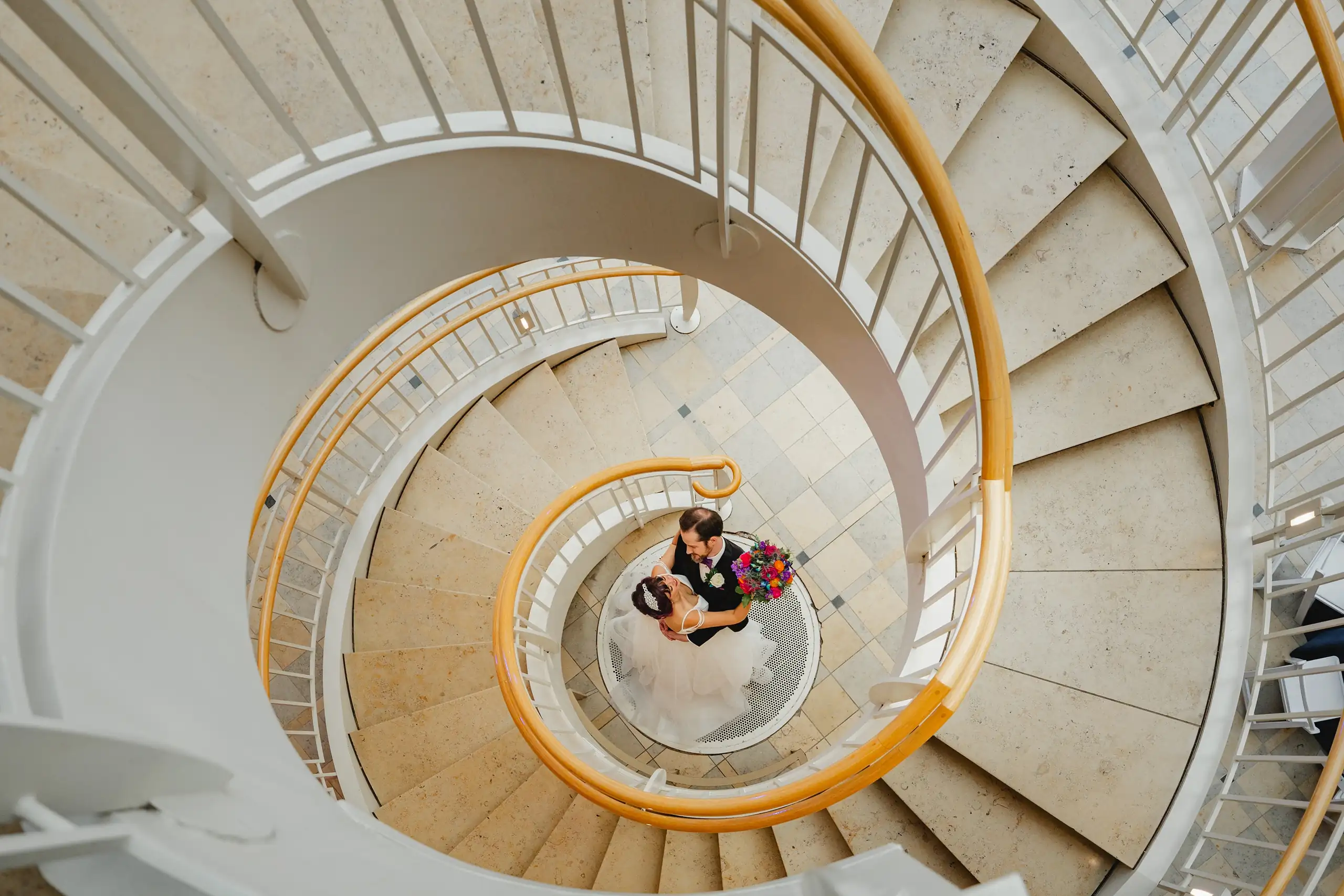 Wedding Formals: the two of them at the foot of the spiral staircase, from above, at their wedding at Fernbank Museum in Atlanta, GA