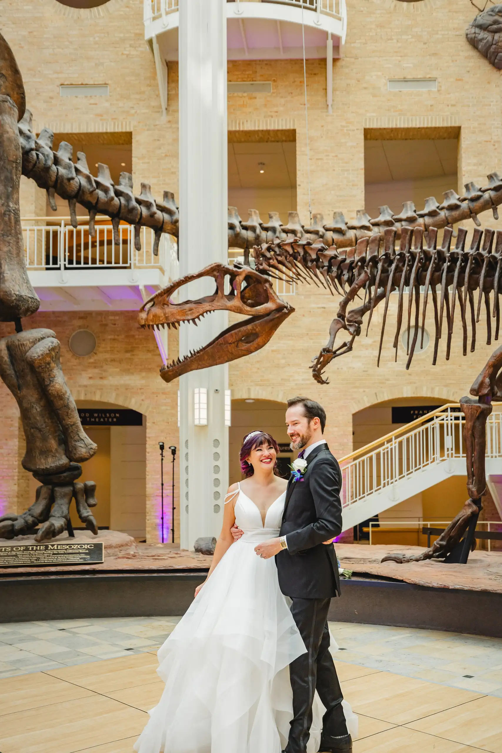 Wedding Formals: the couple beneath the long-necked skeleton, at their wedding at Fernbank Museum in Atlanta, GA