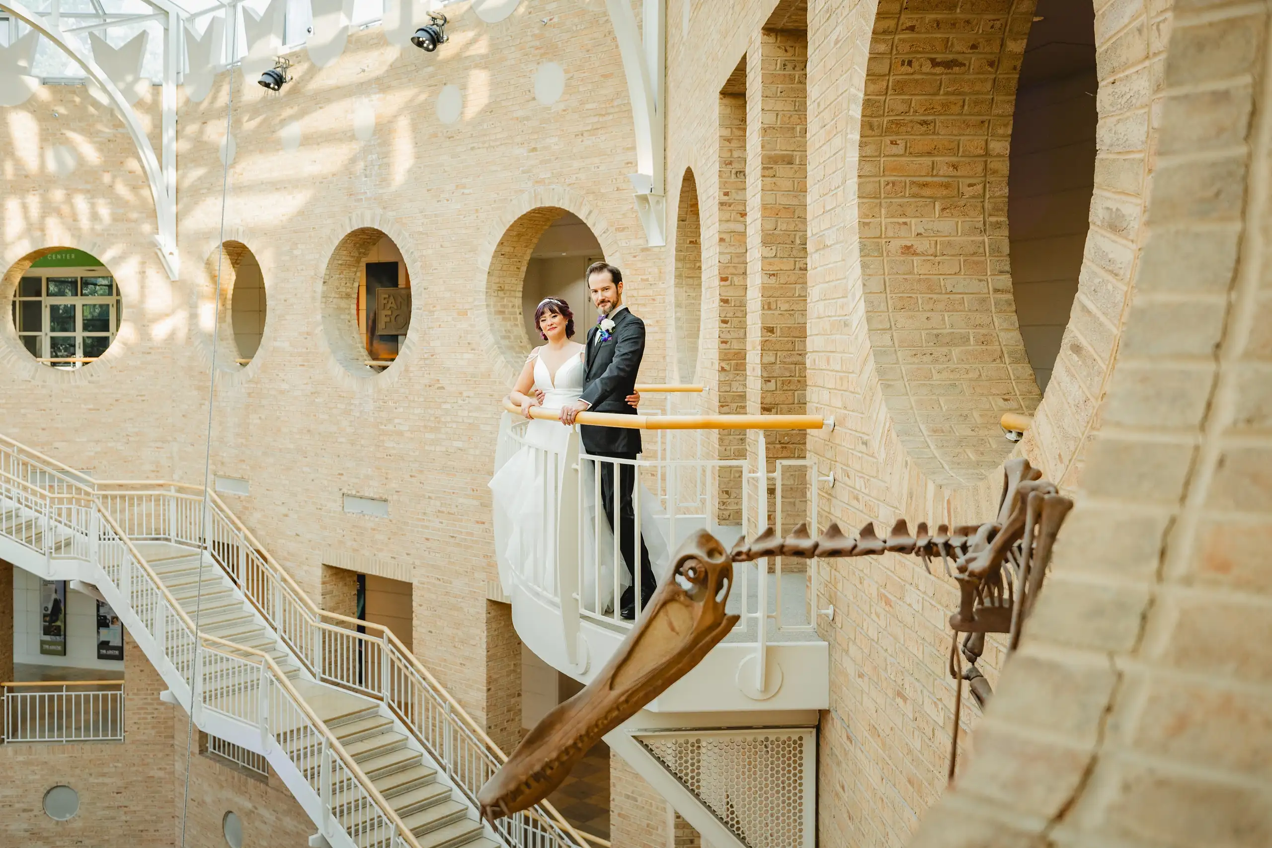 Wedding Formals: the couple on the balcony, the skeleton reaching past them, at their wedding at Fernbank Museum in Atlanta, GA