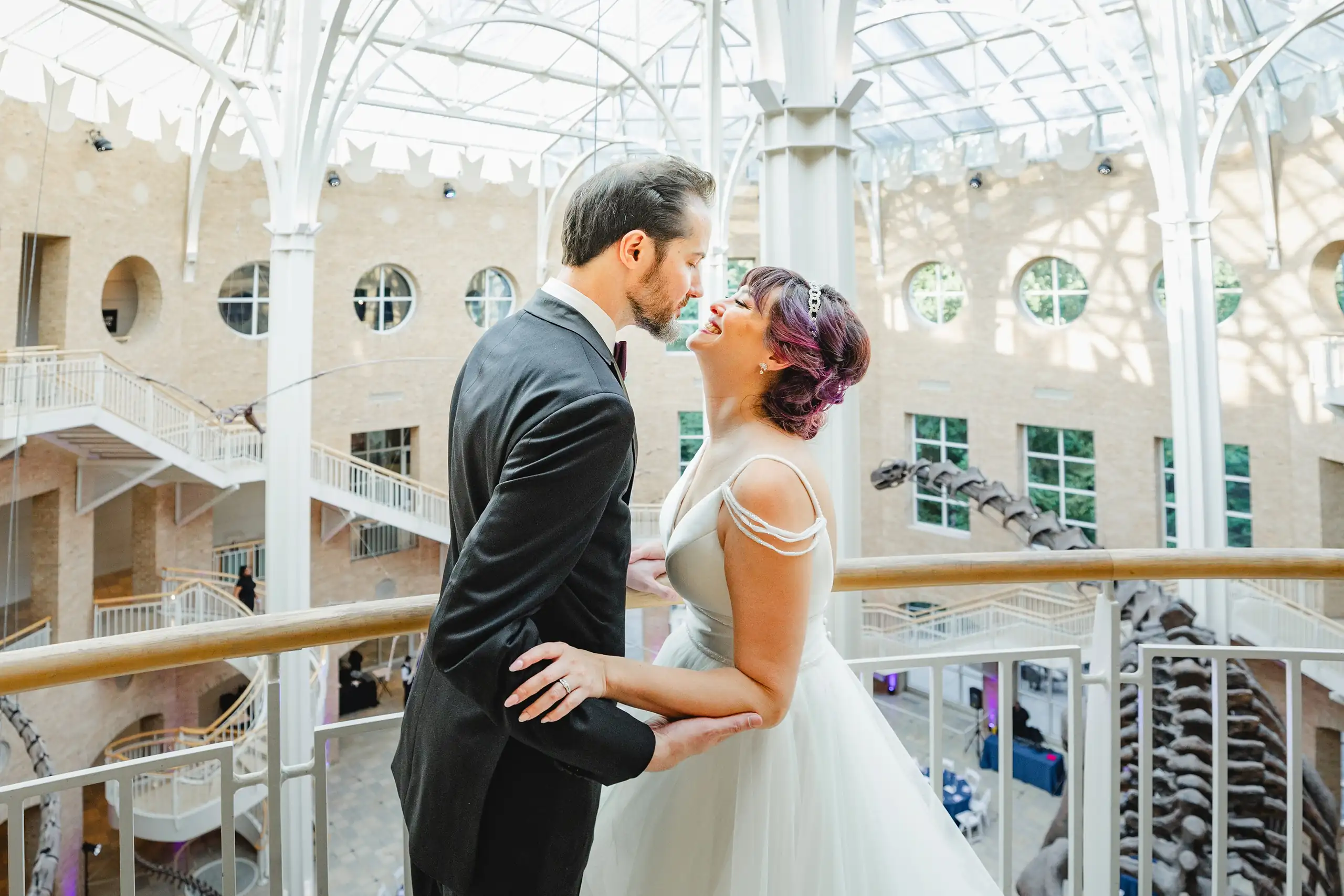 Wedding Formals: a kiss on the balcony under the glass roof, at their wedding at Fernbank Museum in Atlanta, GA