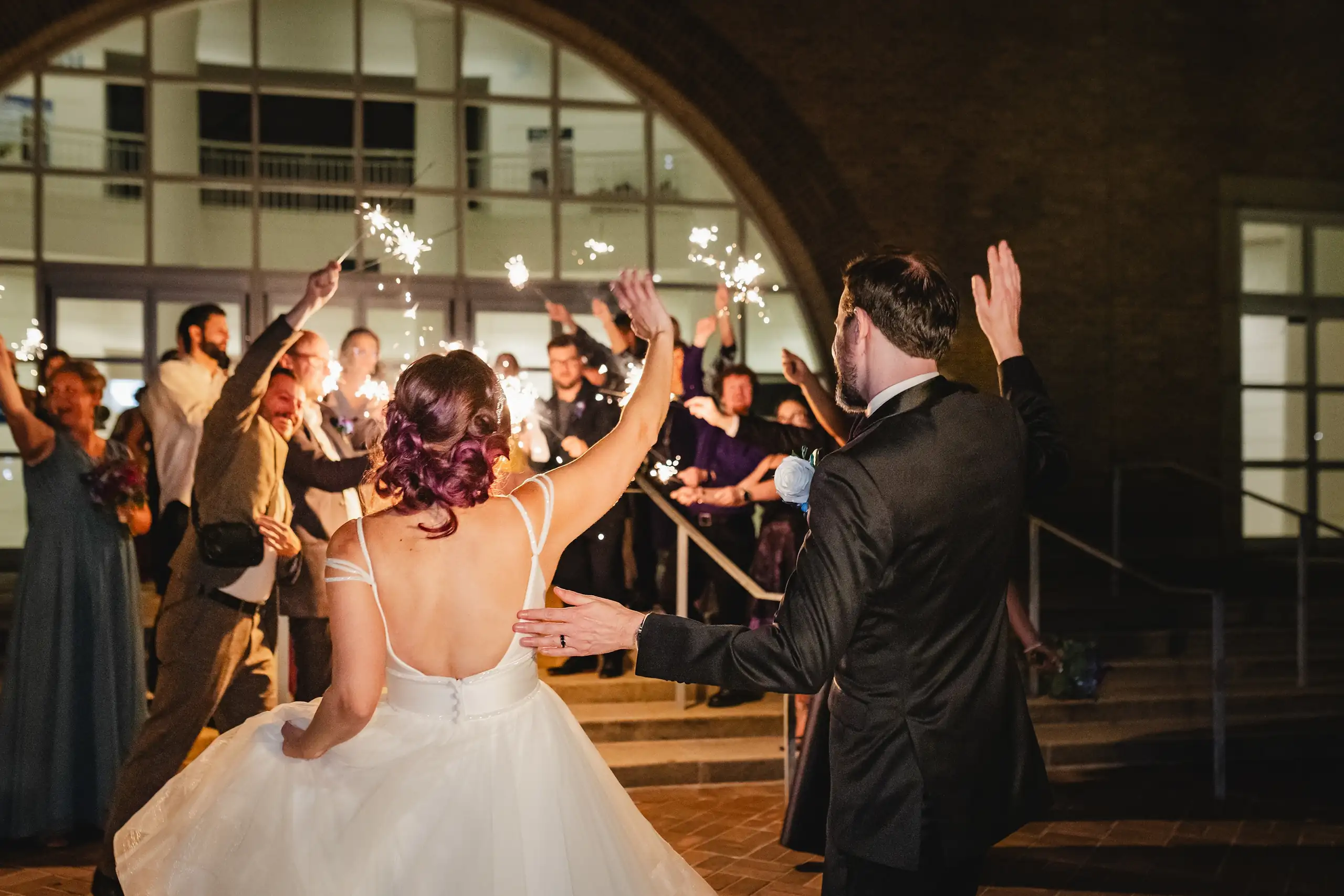 Sparkler Exit: the groom throwing his arms wide in the archway, at their wedding at Fernbank Museum in Atlanta, GA